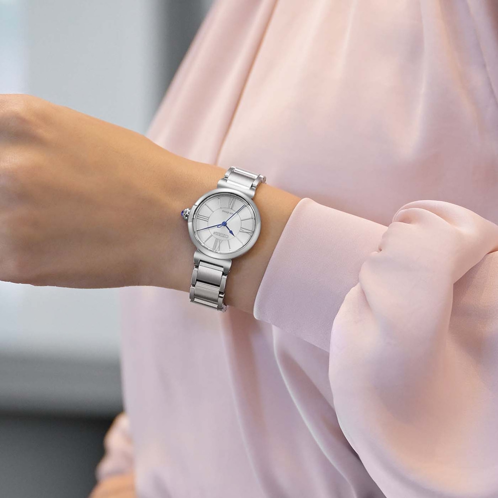 Une femme porte une montre bracelet en argent sur son poignet gauche.