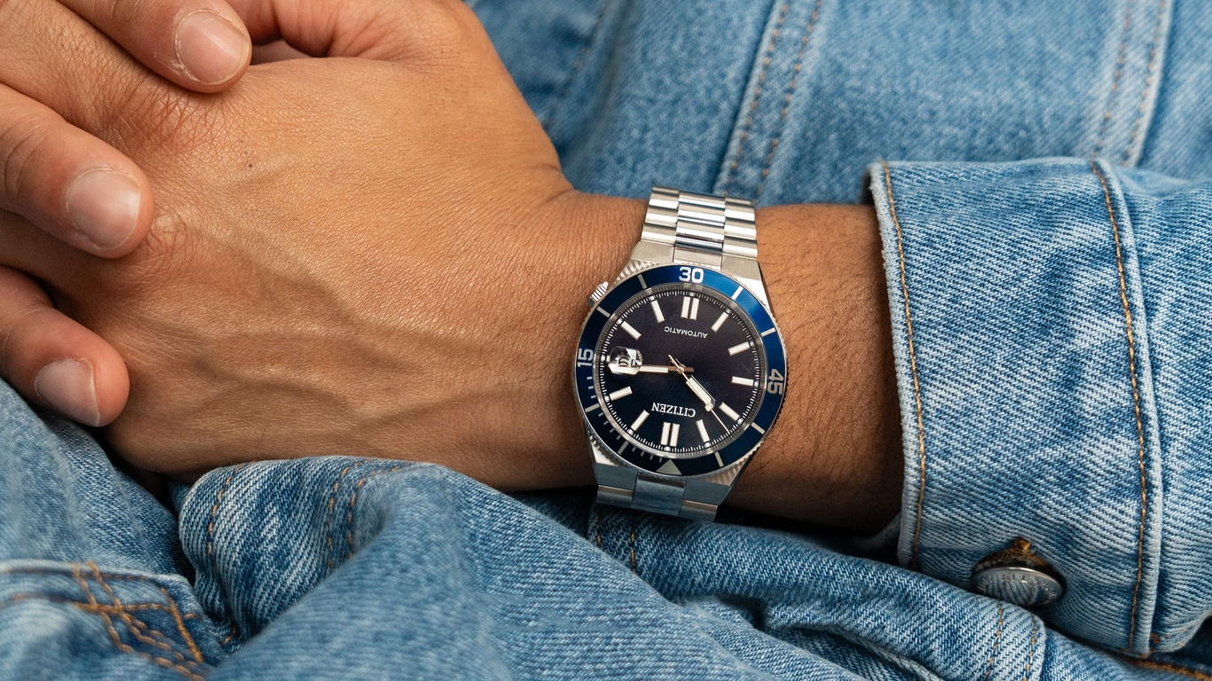 Montre Citizen automatique bleue sur un poignet masculin, vêtue de denim.