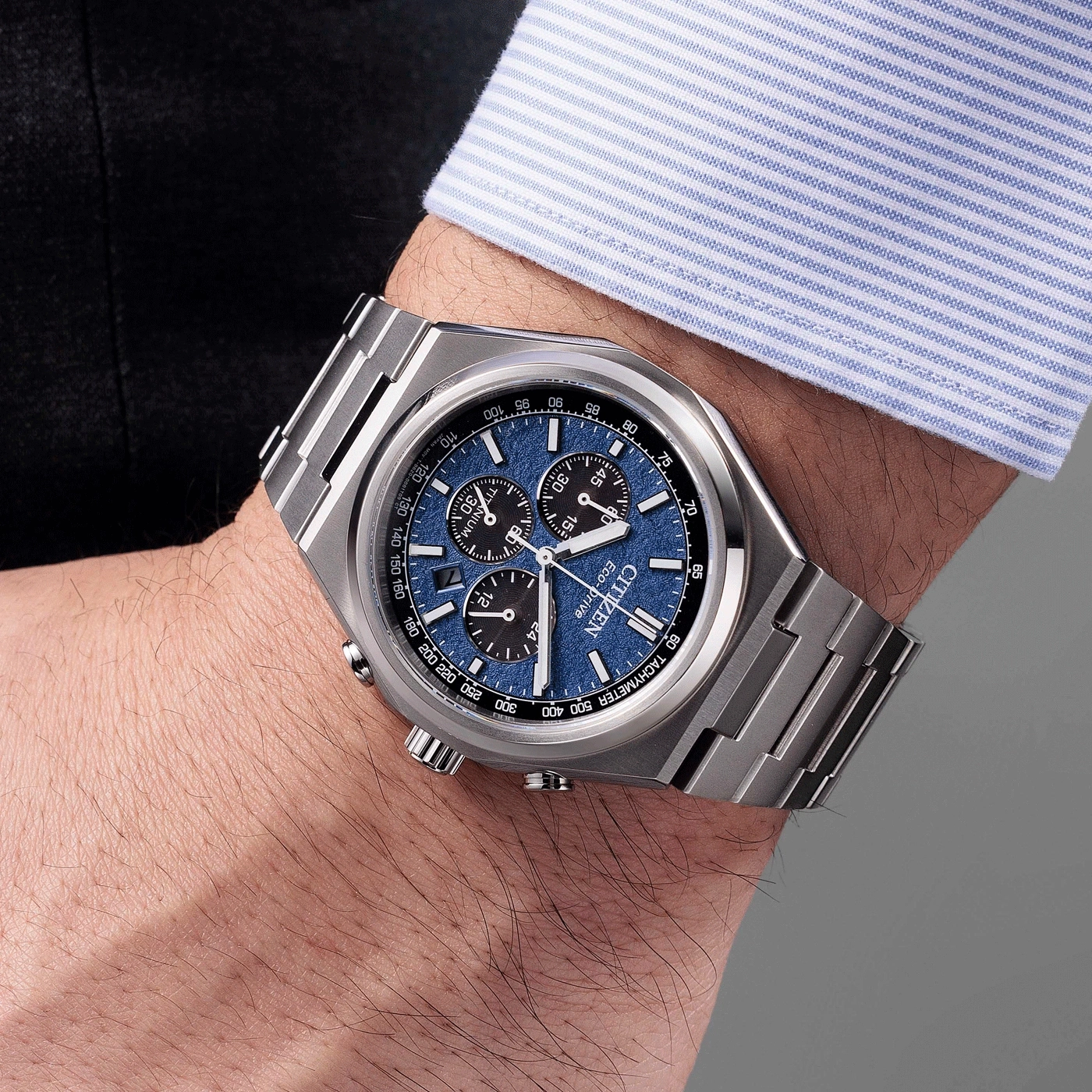 Une montre Citizen argentée avec un cadran bleu, portée au poignet d'un homme.