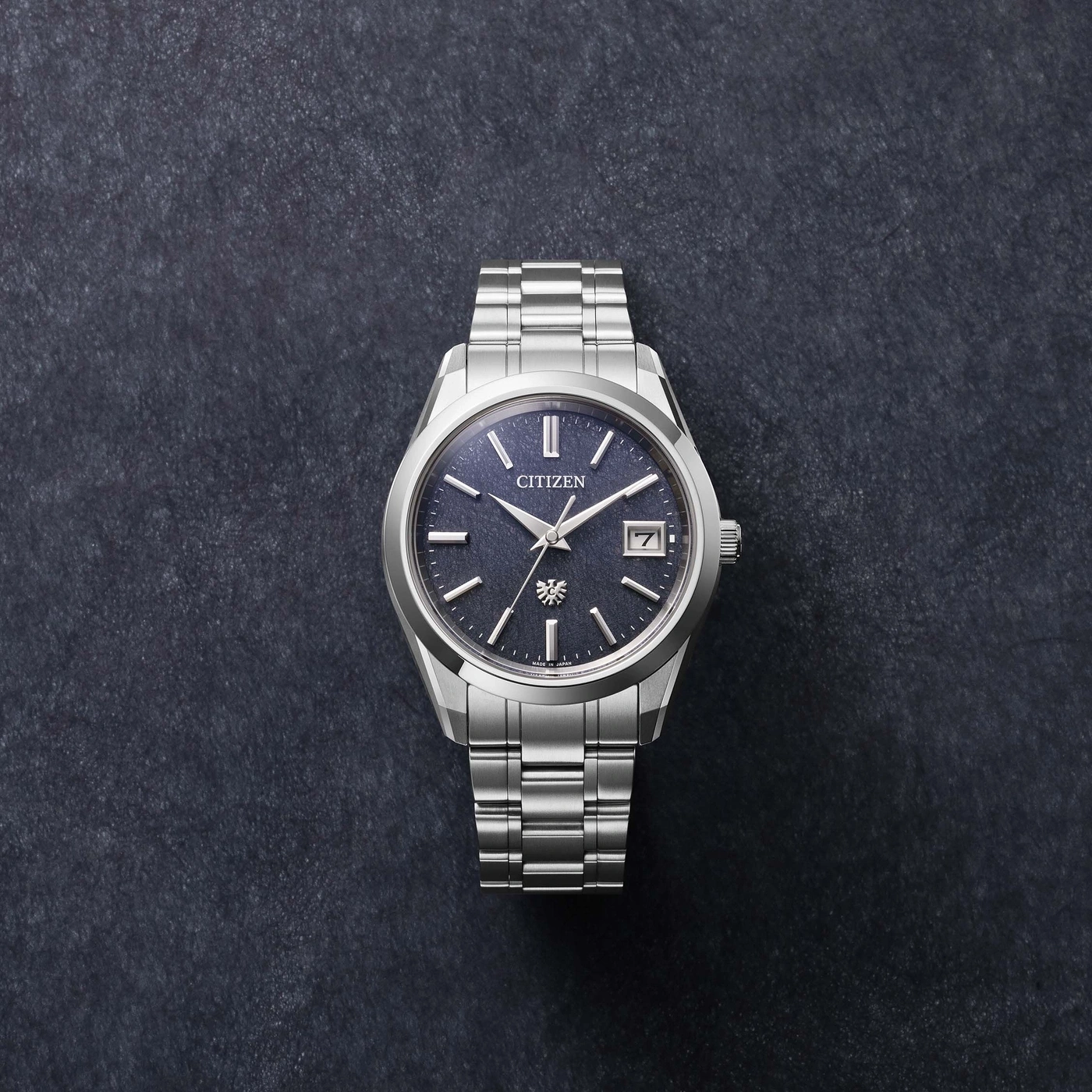 Montre Citizen argentée sur fond sombre, cadran bleu avec date.