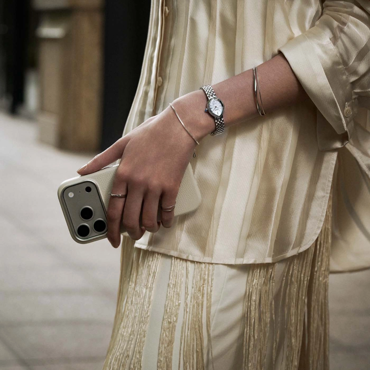 Une femme tenant un téléphone portable et portant une montre et des bracelets.