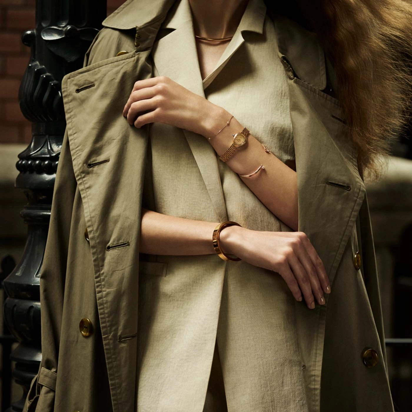 Femme portant un trench beige et des bijoux en or