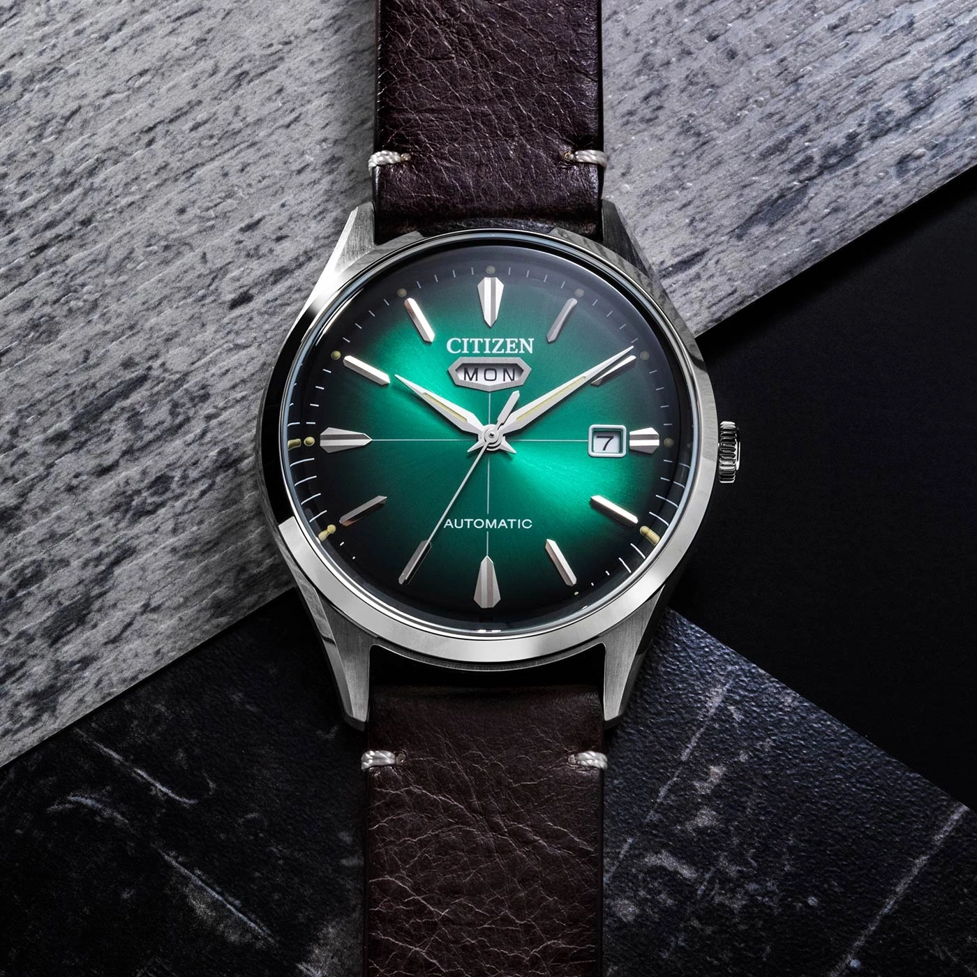 Een groene Citizen automatische horloge op een donkere, getextureerde achtergrond.