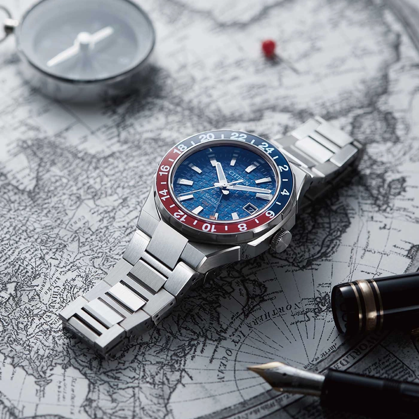 Citizen watch on map with compass and pen, travel theme, blue and red bezel