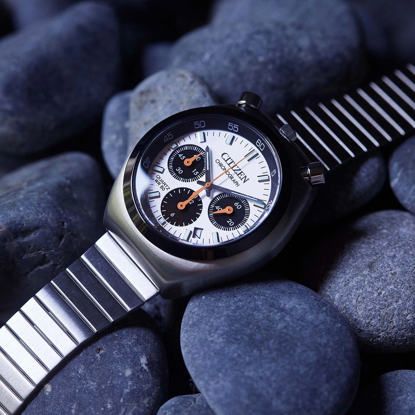 Montre bracelet Citizen chronographe sur fond de galets sombres.