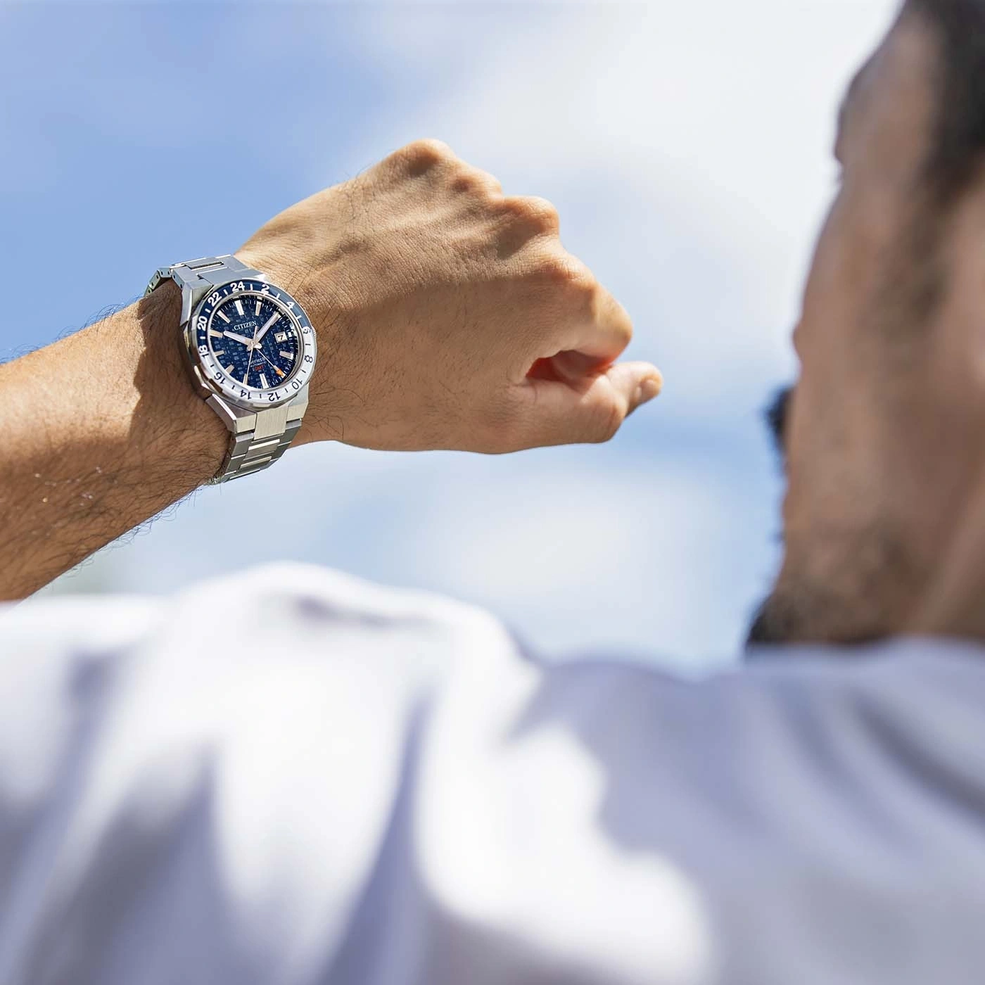 Une personne regarde sa montre citizen avec le ciel bleu en arrière-plan.
