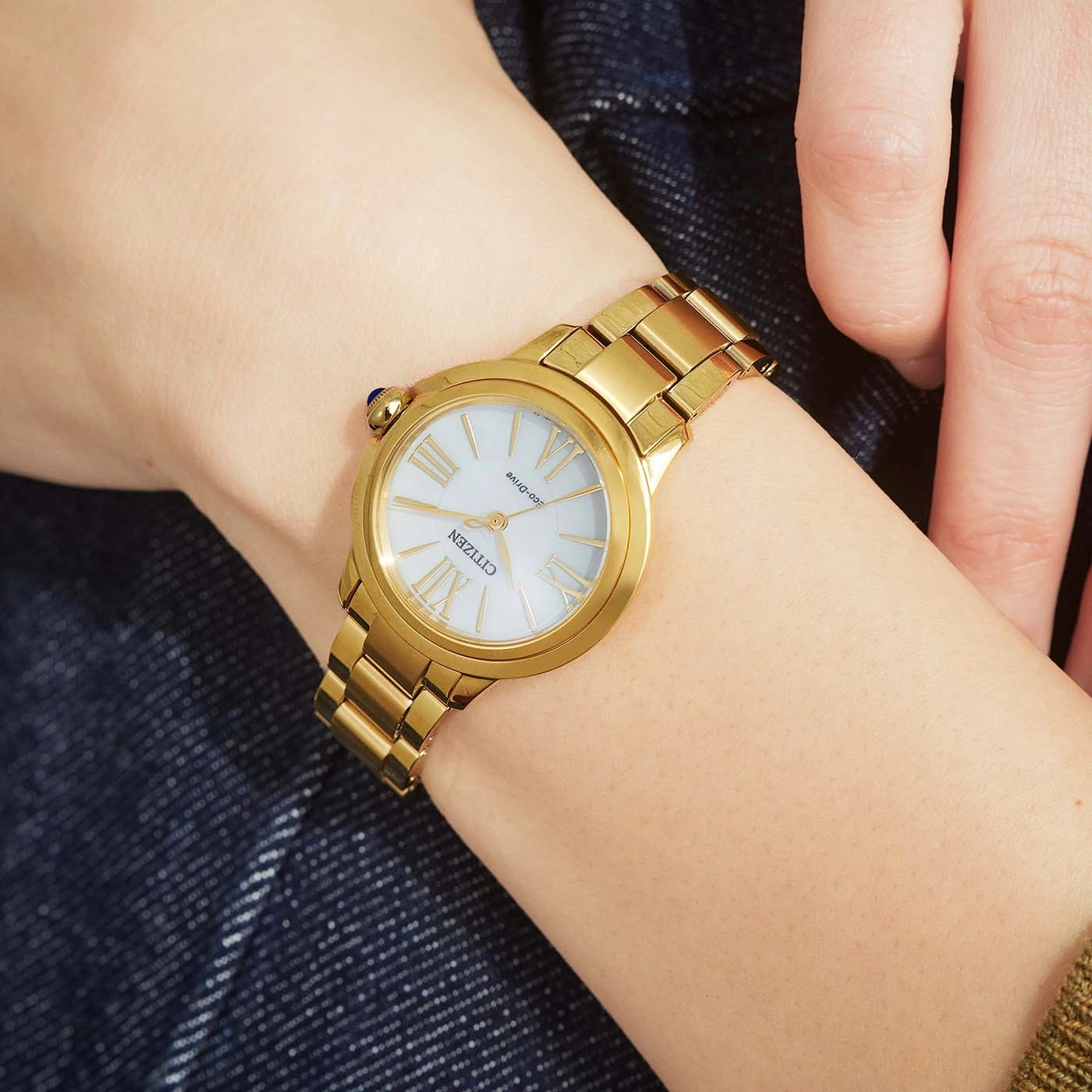 Eine Frau trägt eine goldene Citizen-Uhr am Handgelenk.
