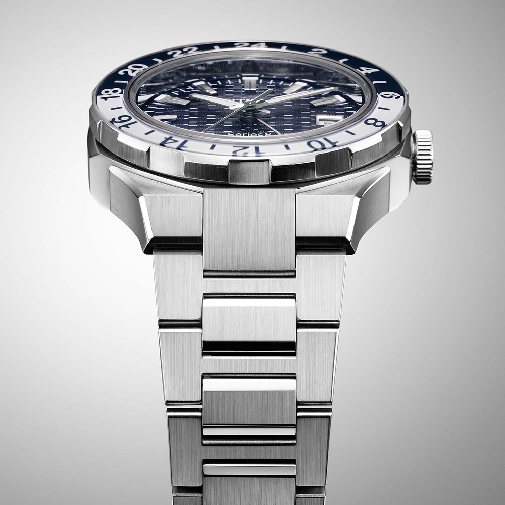 Gros plan d'une montre argentée avec une lunette bleue et blanche et un bracelet en métal.