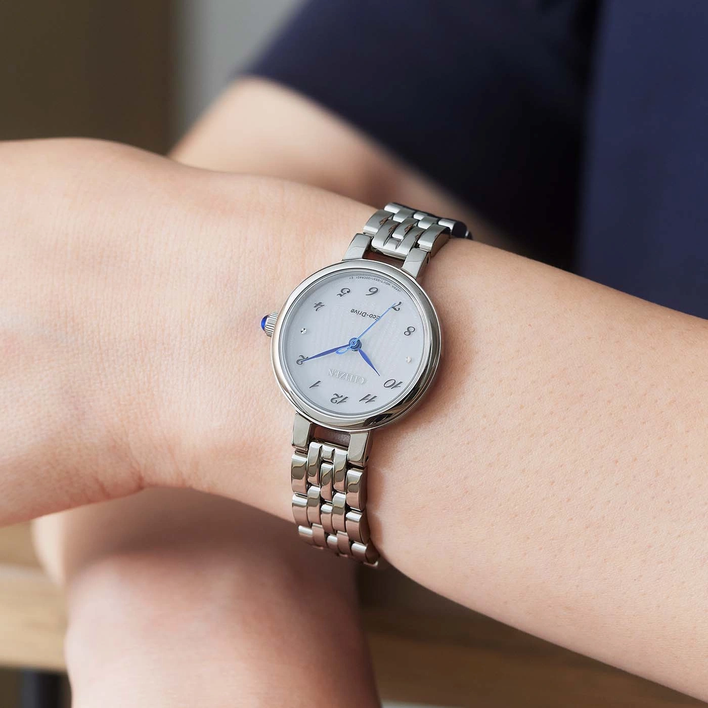 Une femme porte une montre Citizen argentée au poignet.