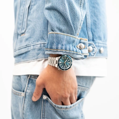 Homme portant une veste en jean avec une montre bleue au poignet.