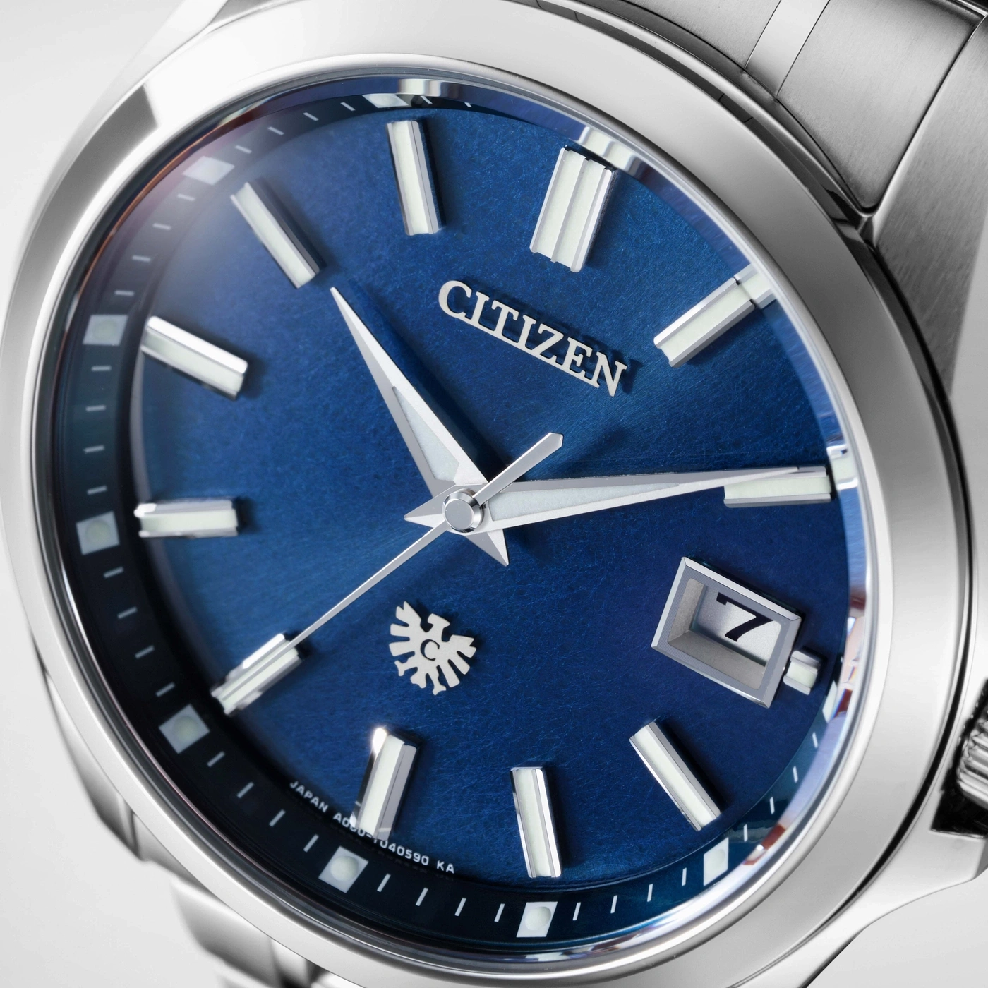 Close-up van de blauwe wijzerplaat van een Citizen horloge met zilveren indexen.