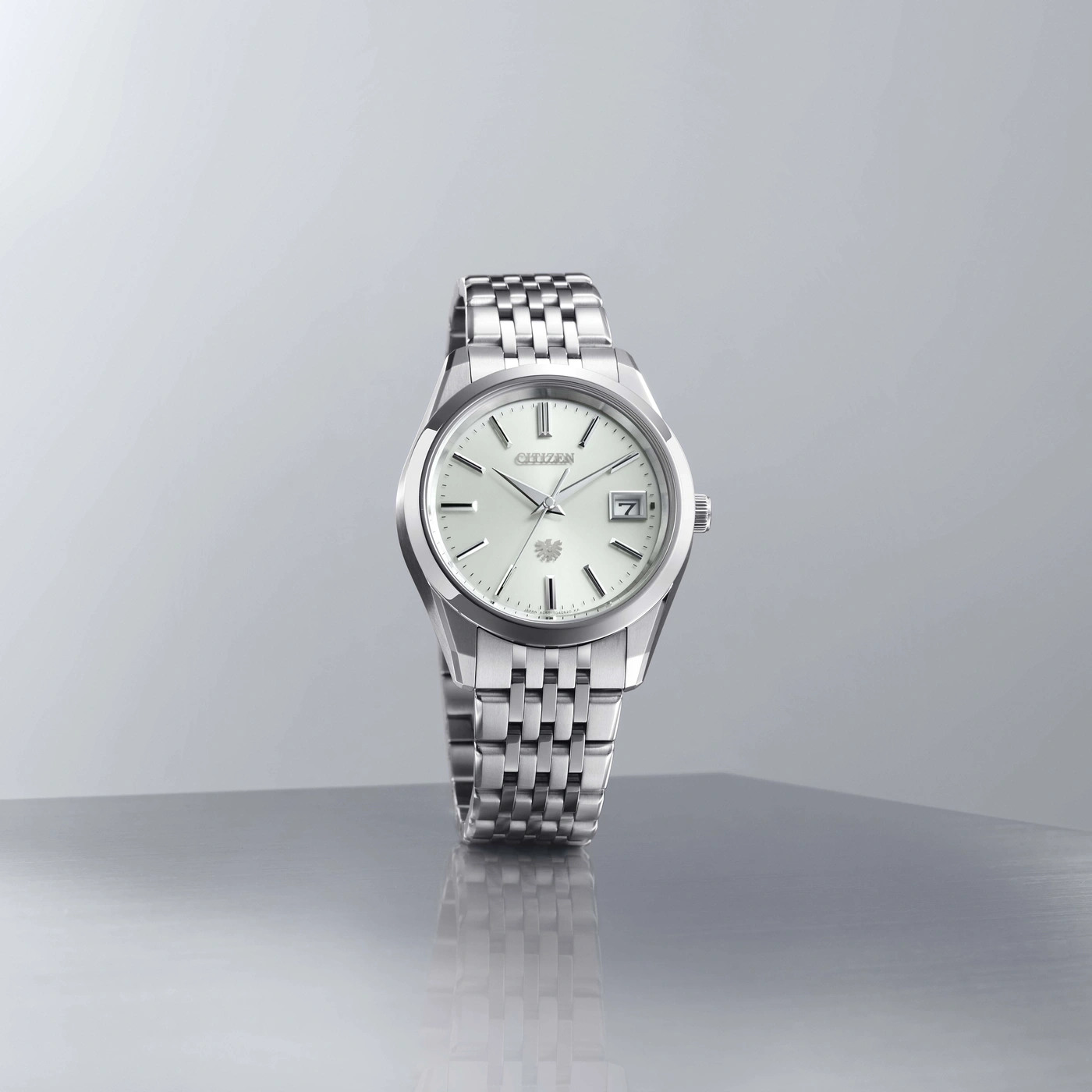 Une montre Citizen argentée avec un cadran blanc et un bracelet en métal.