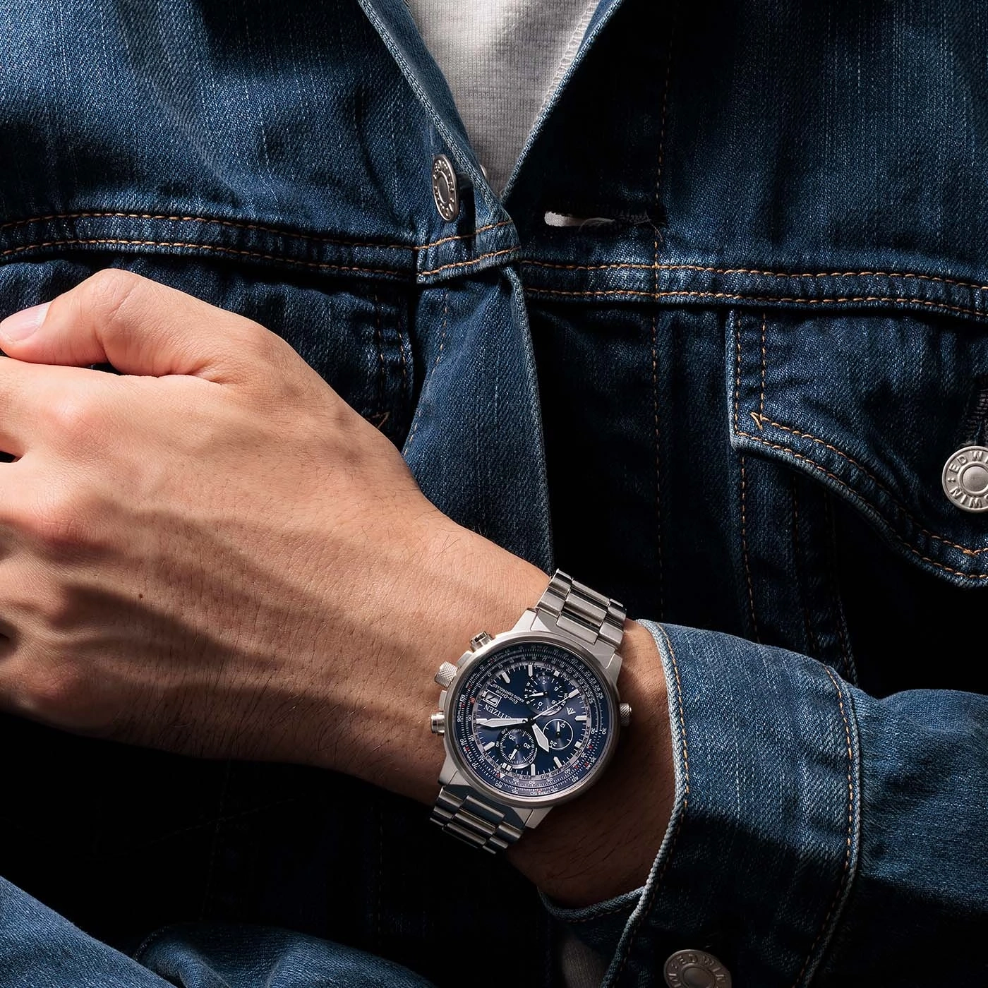 Un homme portant une veste en jean avec une montre Citizen au poignet.