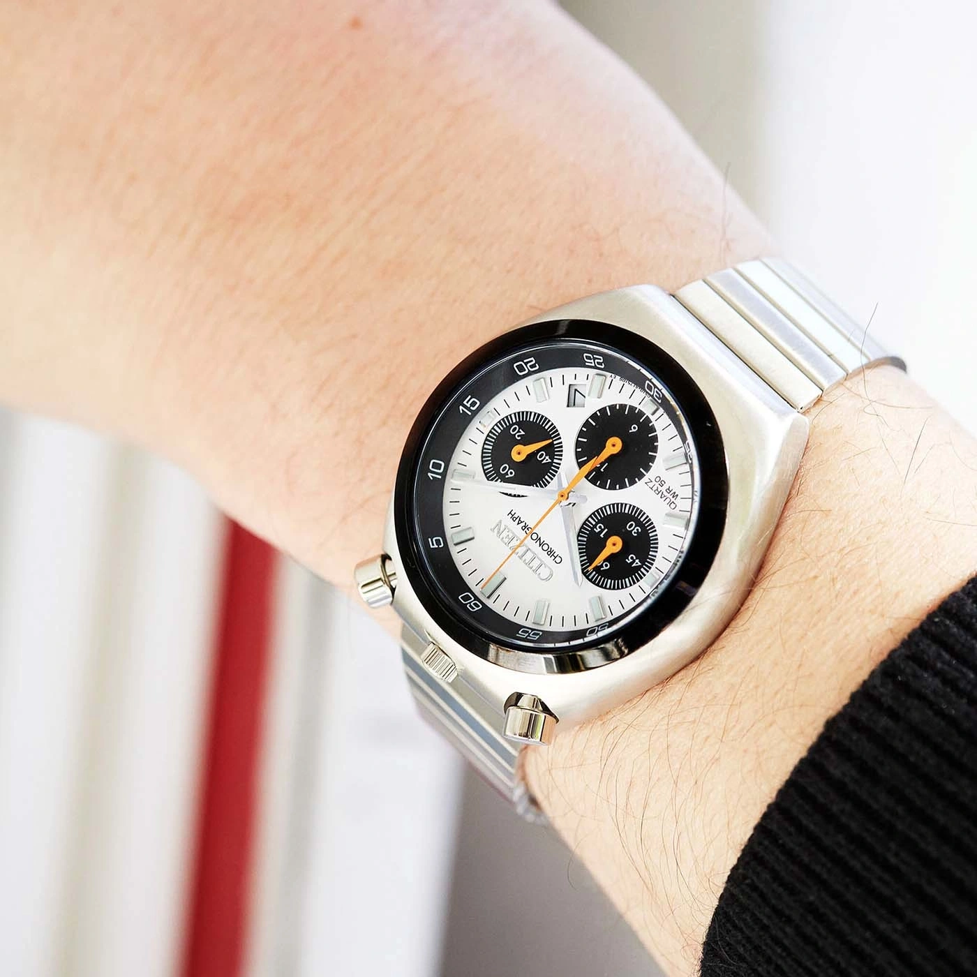 Une montre Citizen chronographe argentée avec un cadran blanc portée au poignet.