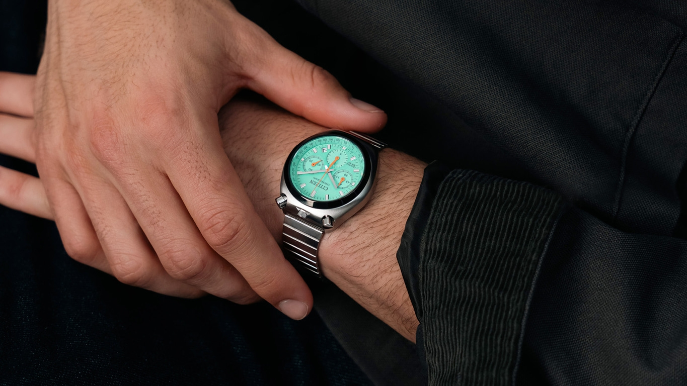 Un homme porte une montre Citizen verte sur son poignet avec un bracelet métallique.
