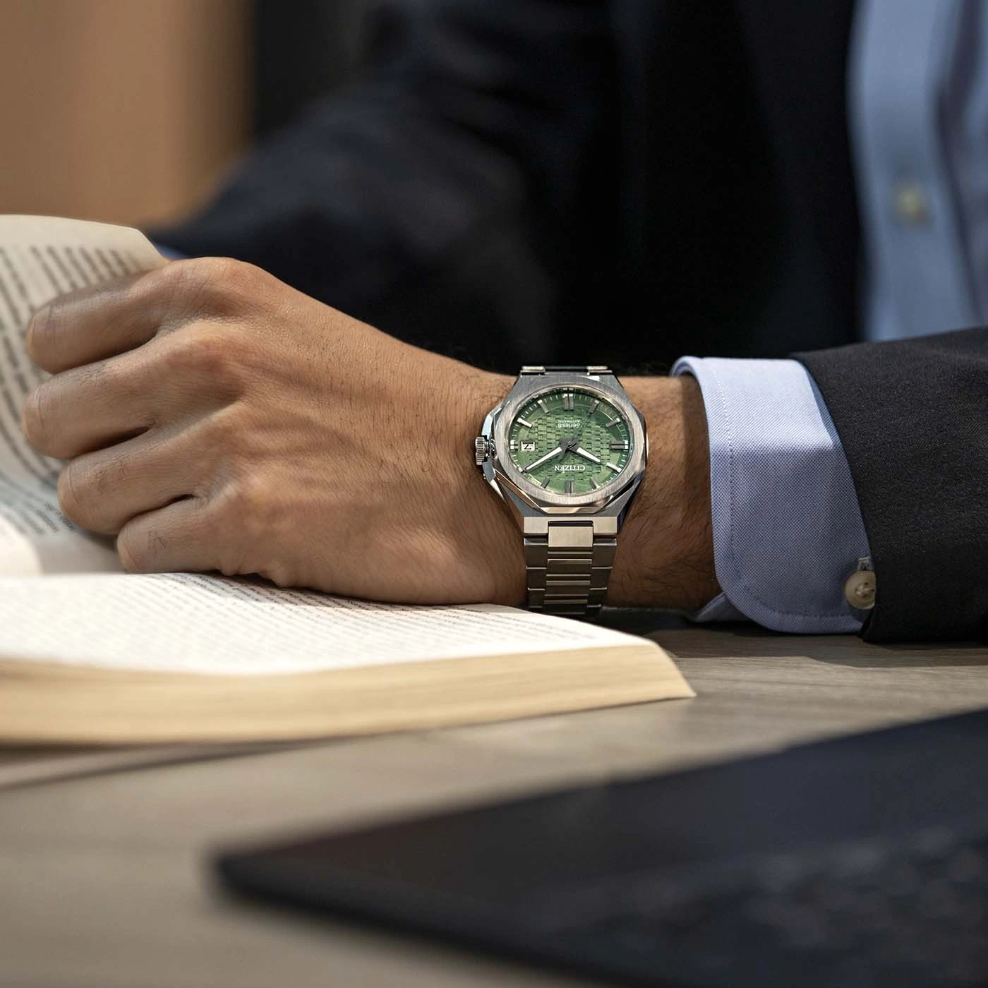 Homme d'affaires portant une montre verte lisant un livre sur un bureau