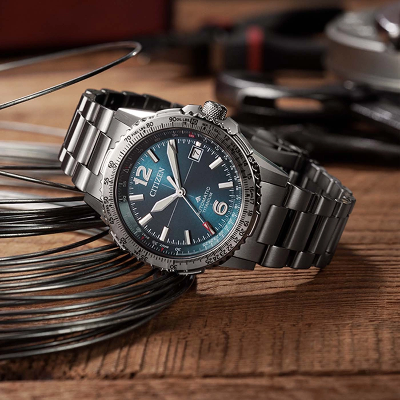 Une montre homme Citizen automatique en titane est posée sur un fond en bois