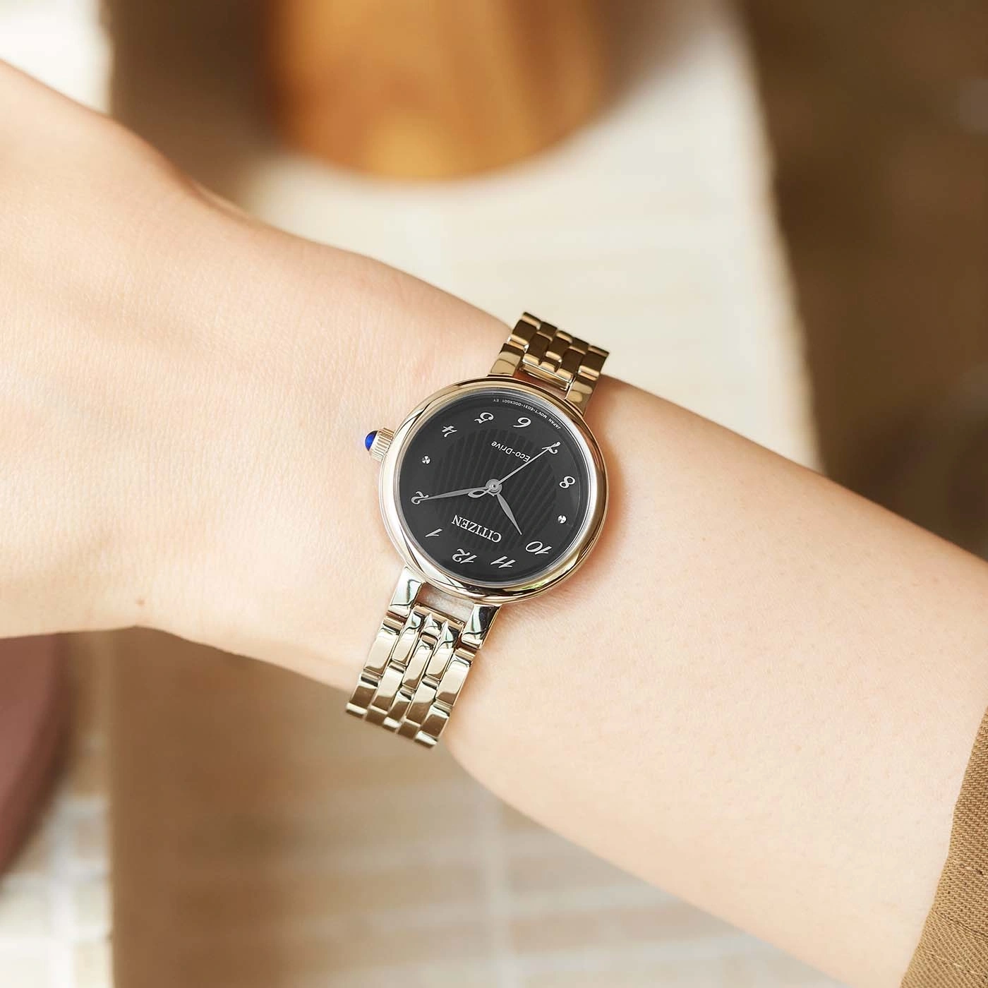 Montre bracelet Citizen sur un poignet, cadran noir et bracelet argenté.