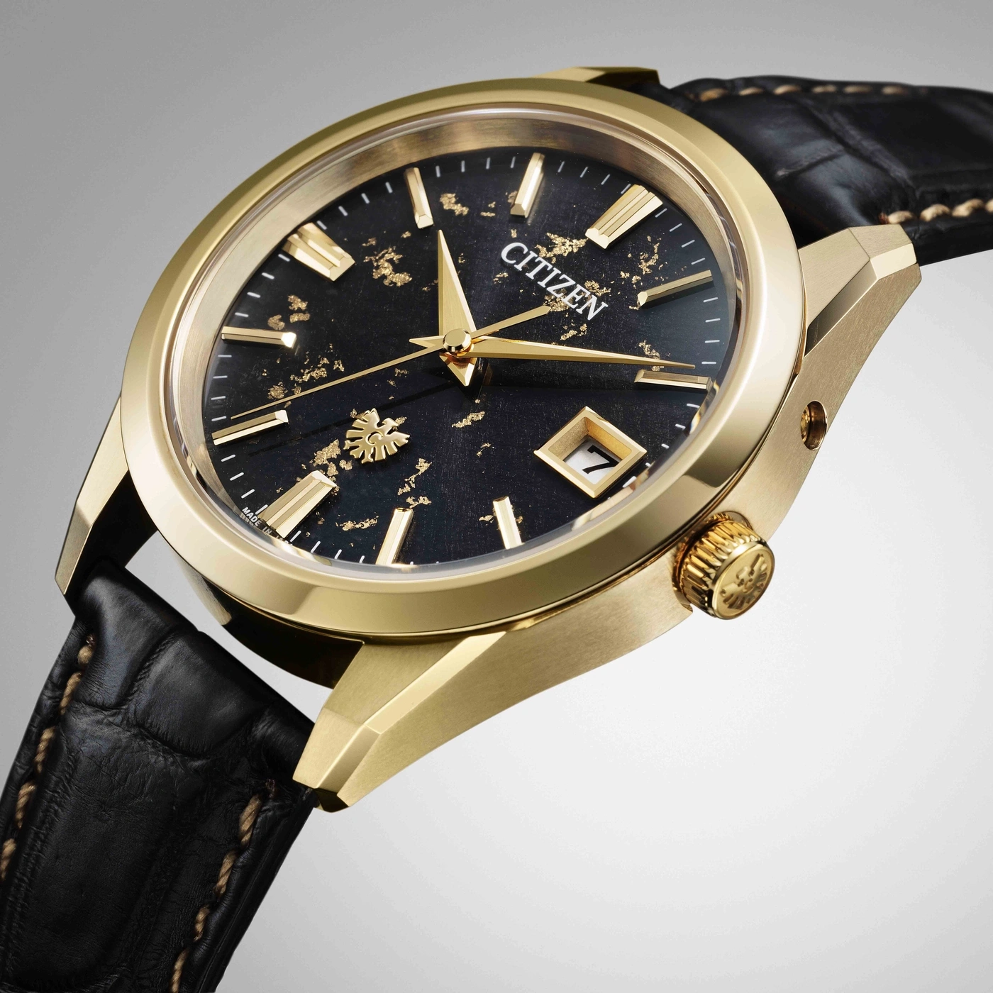 Montre Citizen dorée avec cadran noir texturé et bracelet en cuir noir.