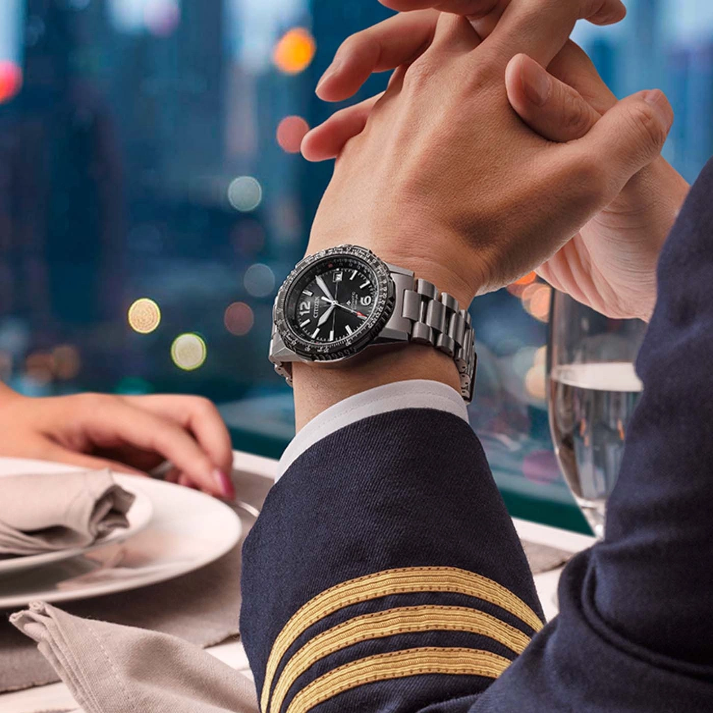 Un homme portant une montre Citizen et un uniforme de pilote assis à table.