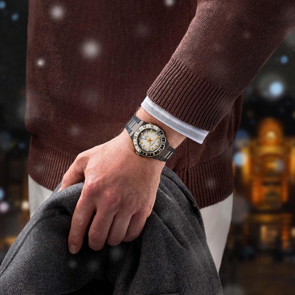 Homme portant une montre, tenant un manteau, fond flou, hiver.