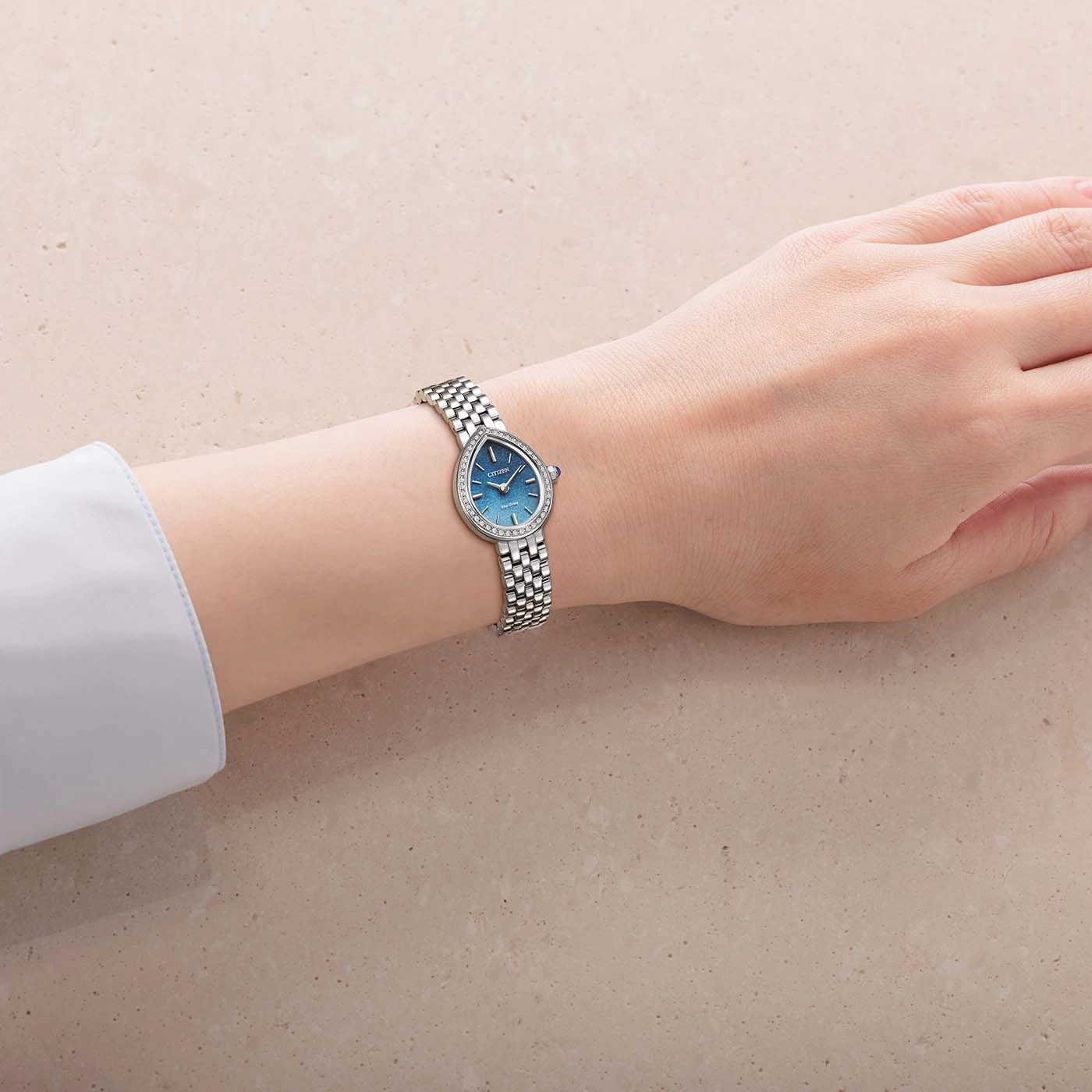Eine Hand trägt eine Citizen-Uhr mit blauem Zifferblatt und silbernem Armband.