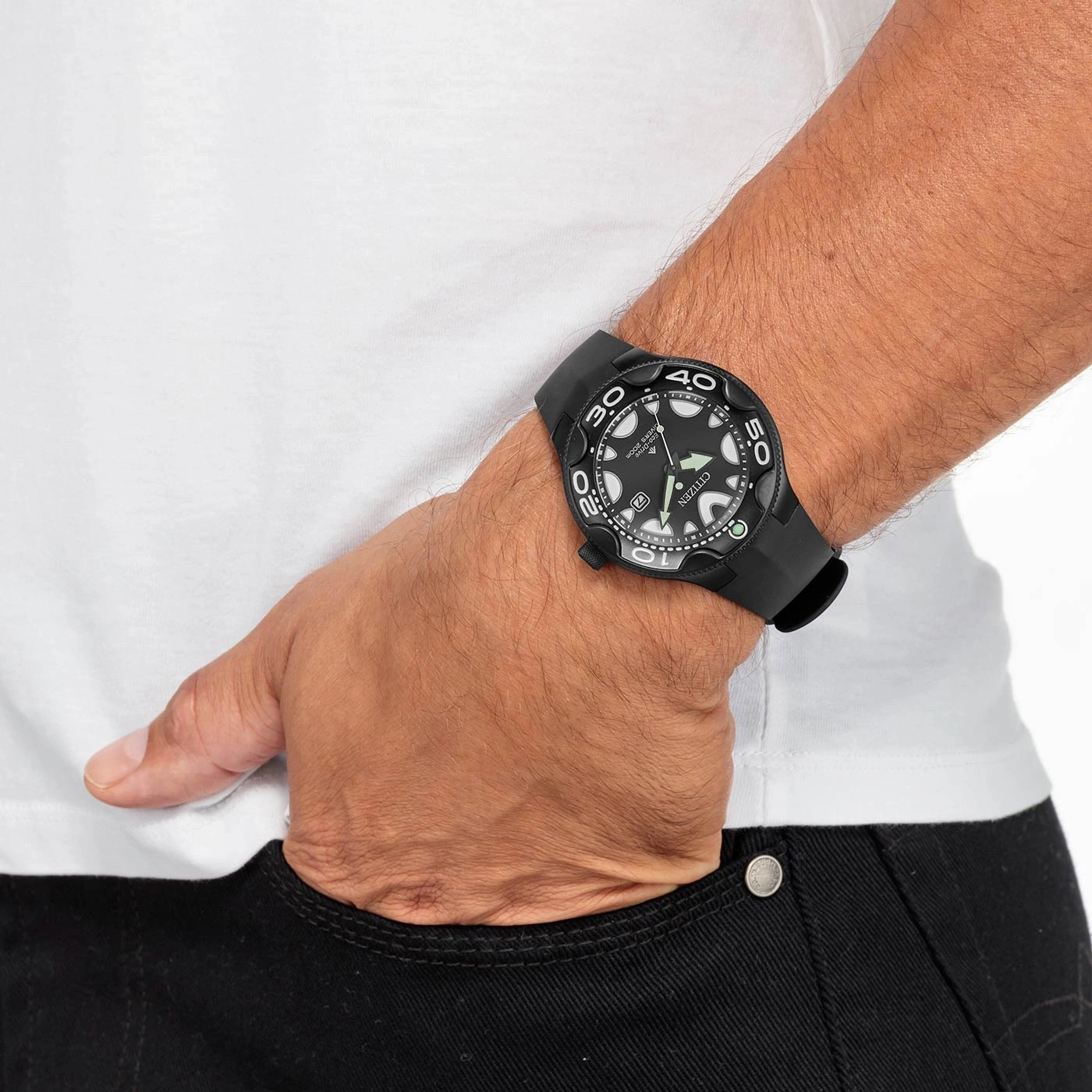 Un homme porte une montre noire Citizen sur son poignet avec sa main dans la poche.