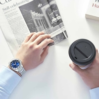 Homme tenant un journal et un café, portant une montre.