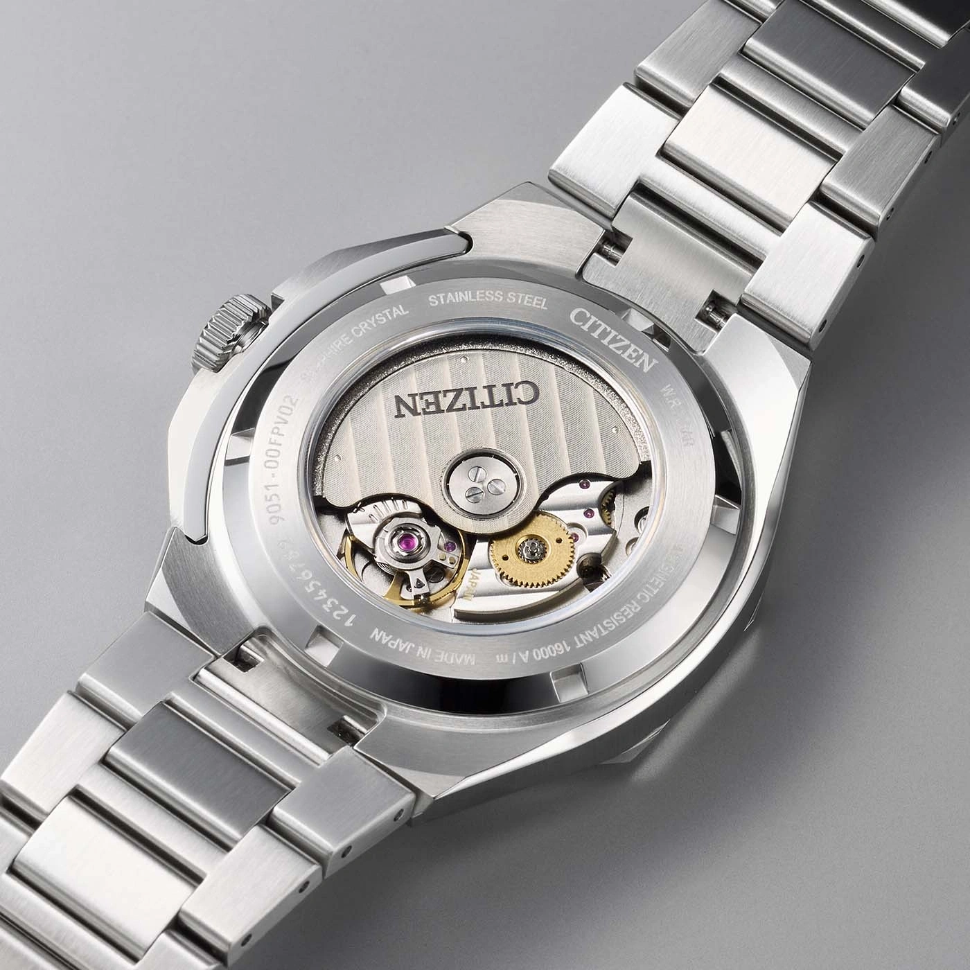 Le dos d'une montre Citizen avec mouvement visible et bracelet en acier.