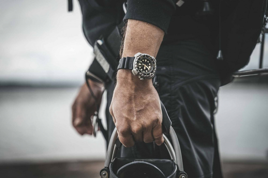 Homme portant une montre, tenant de l'équipement, gros plan, tenue noire