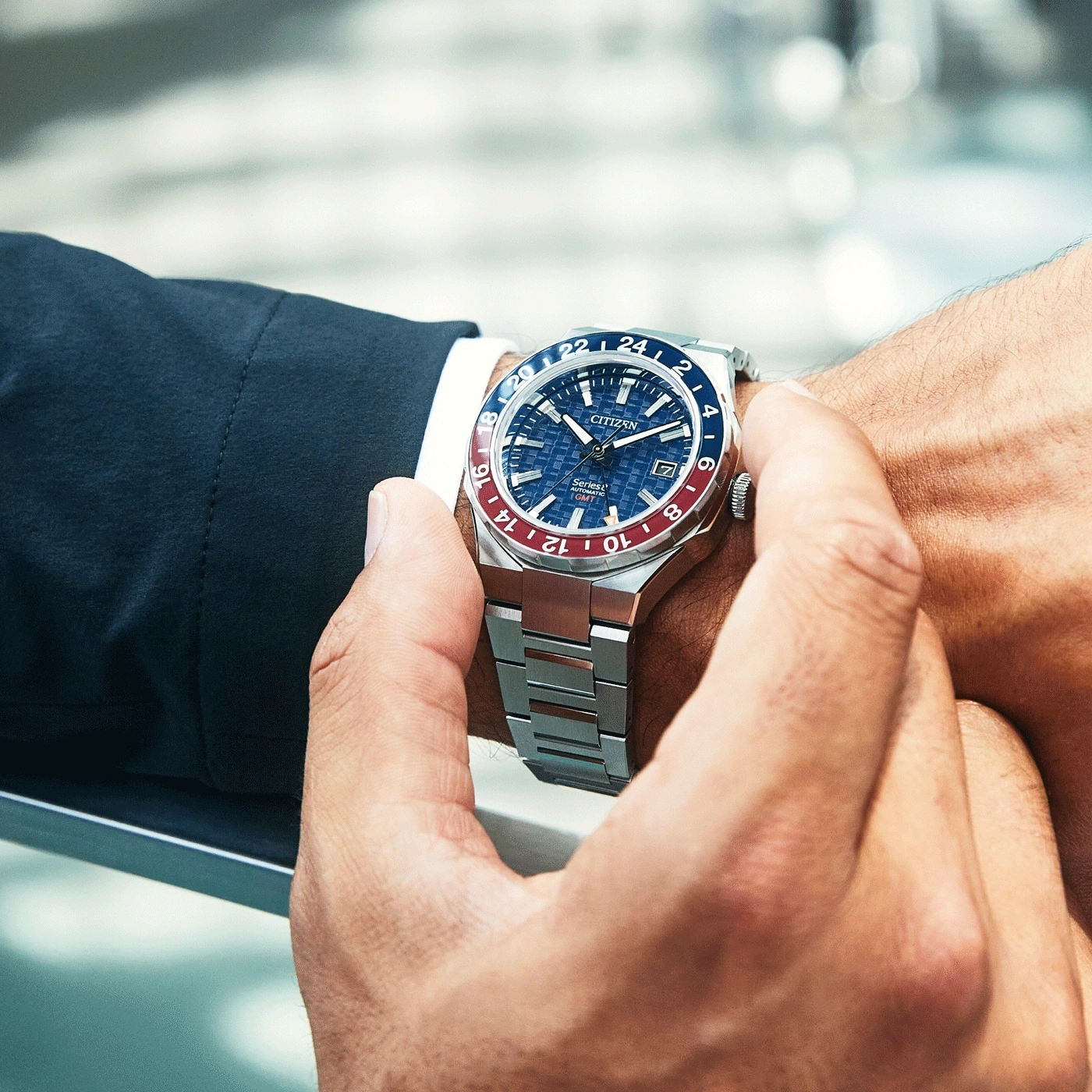 Homme regardant sa montre Citizen automatique GMT avec lunette rouge et bleue.