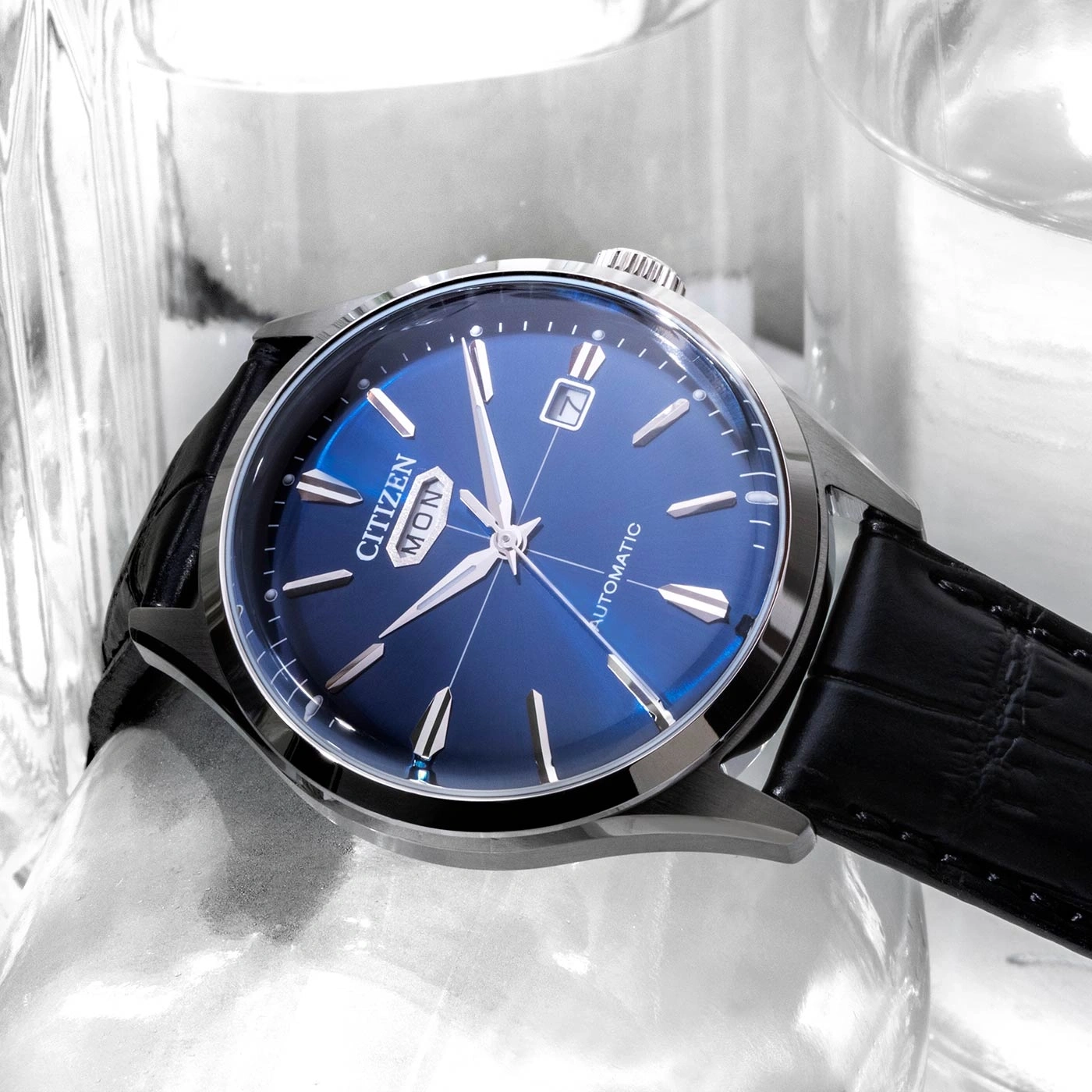 Citizen horloge blauw met zwarte leren band en dag- en datumweergave.