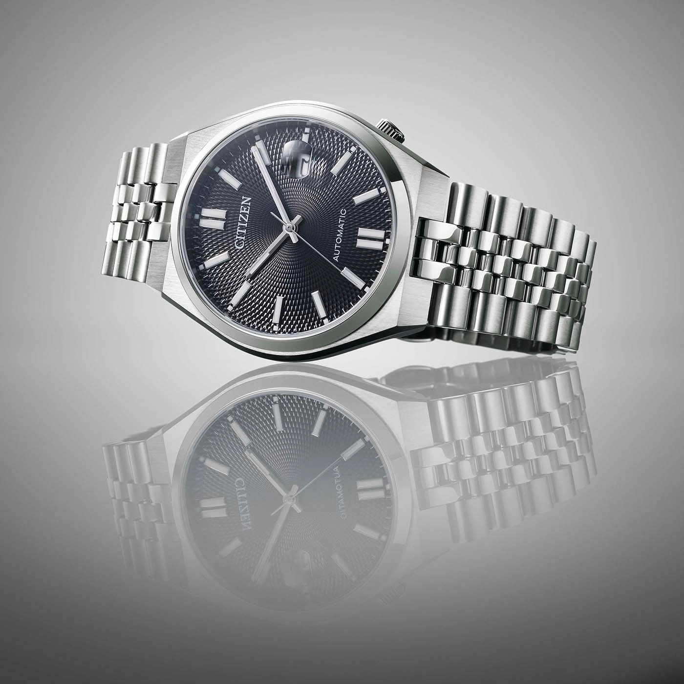 Zilveren Citizen automatische horloge op grijze achtergrond met reflectie.