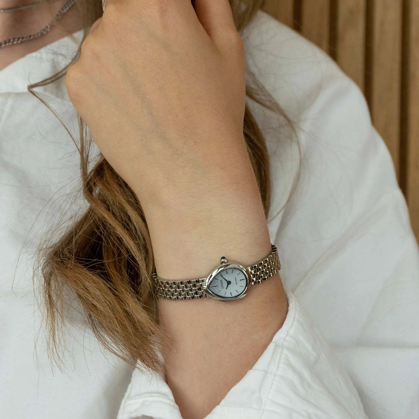 Une montre bracelet fine avec un cadran ovale gris sur un poignet