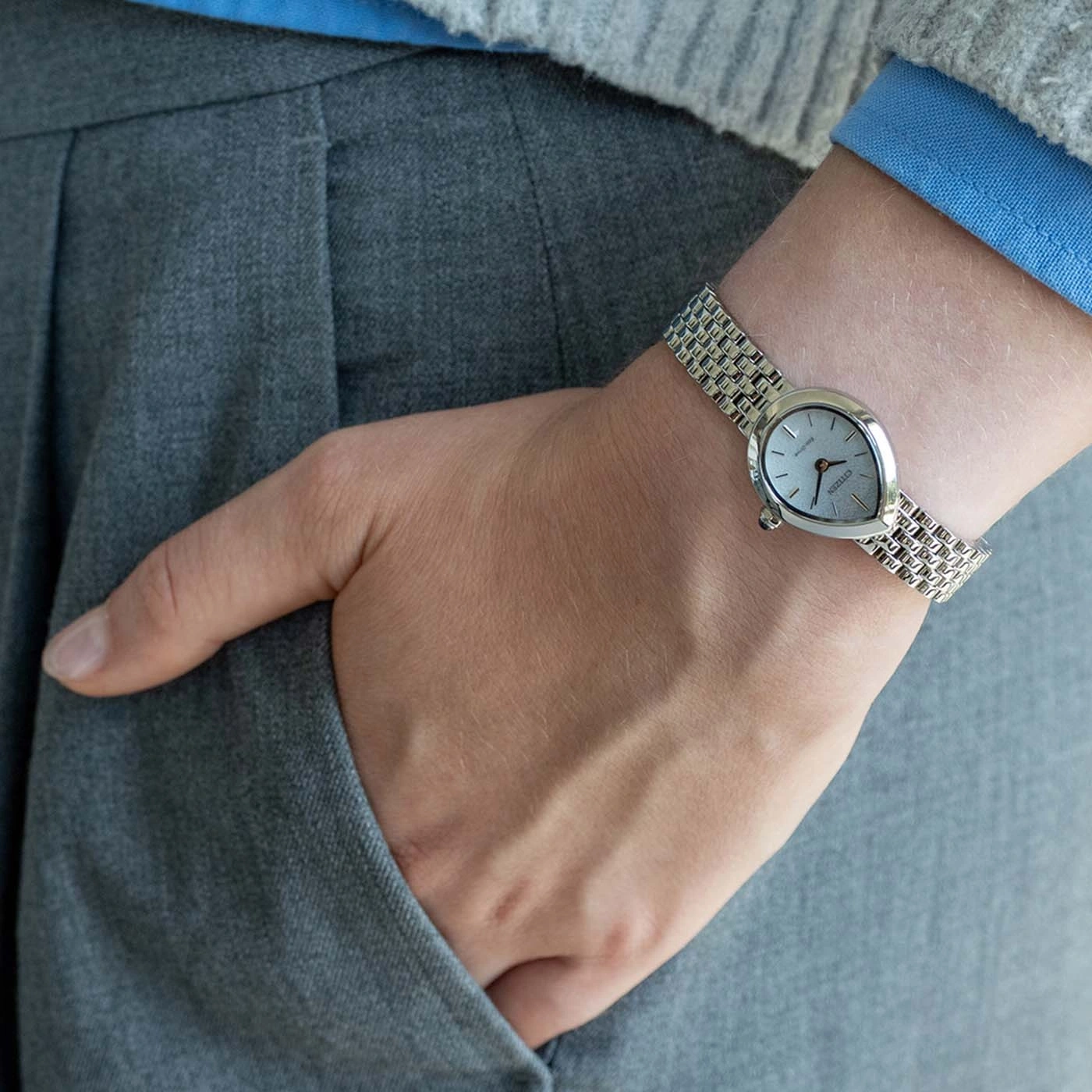 Une personne portant une montre-bracelet argentée sur un pantalon gris