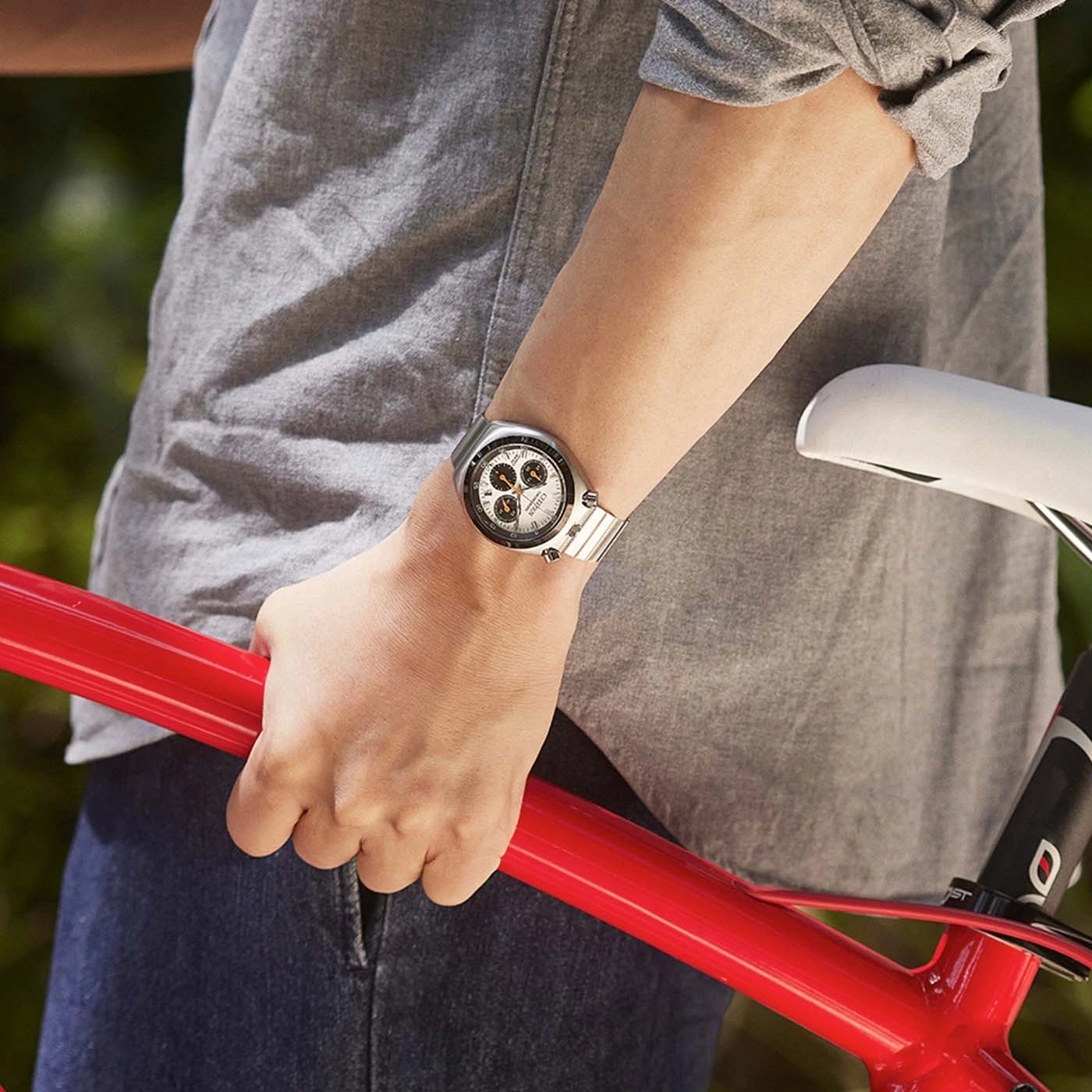 Homme tenant un vélo rouge portant une montre Citizen.