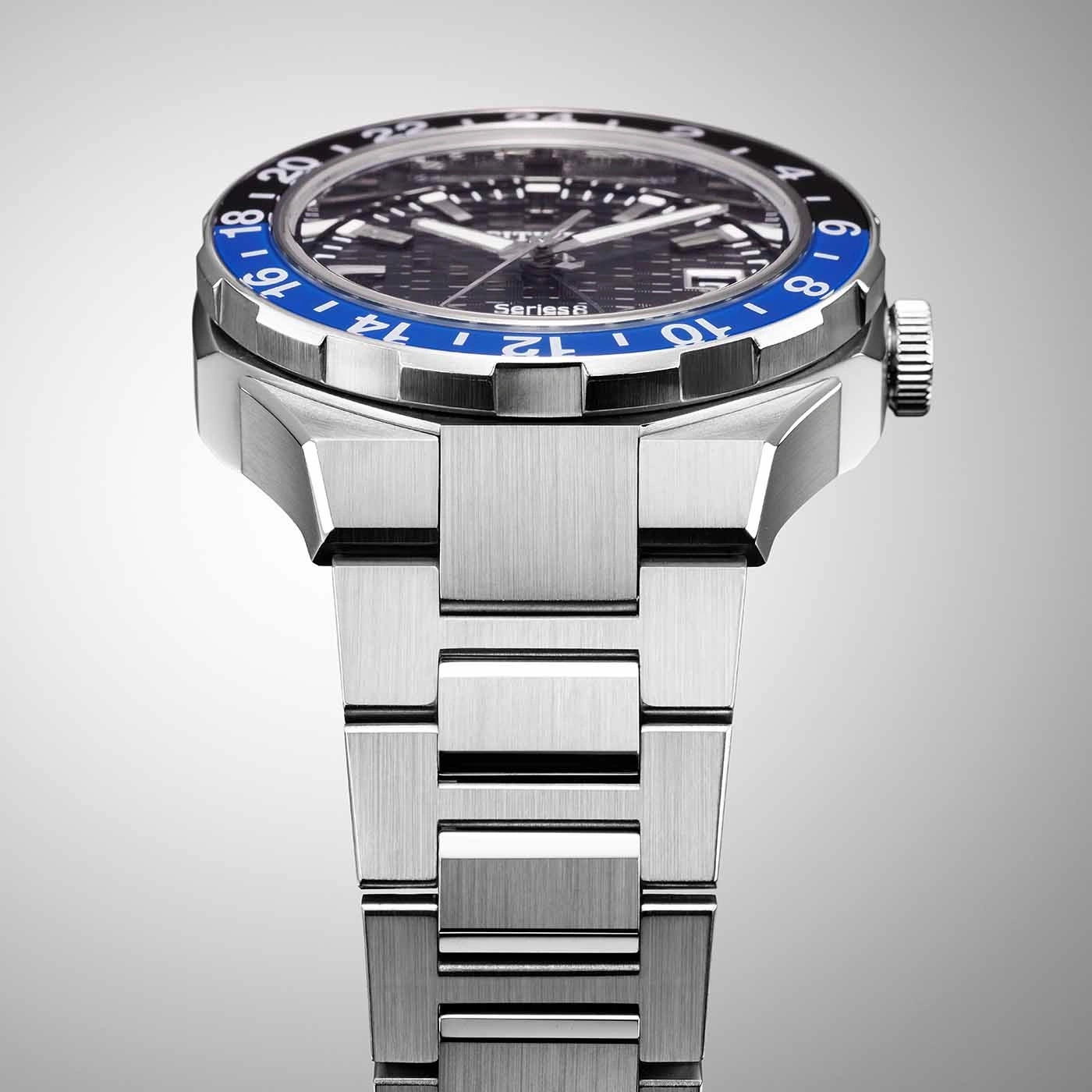 Close-up of a silver watch with a blue and black bezel and a metal strap.