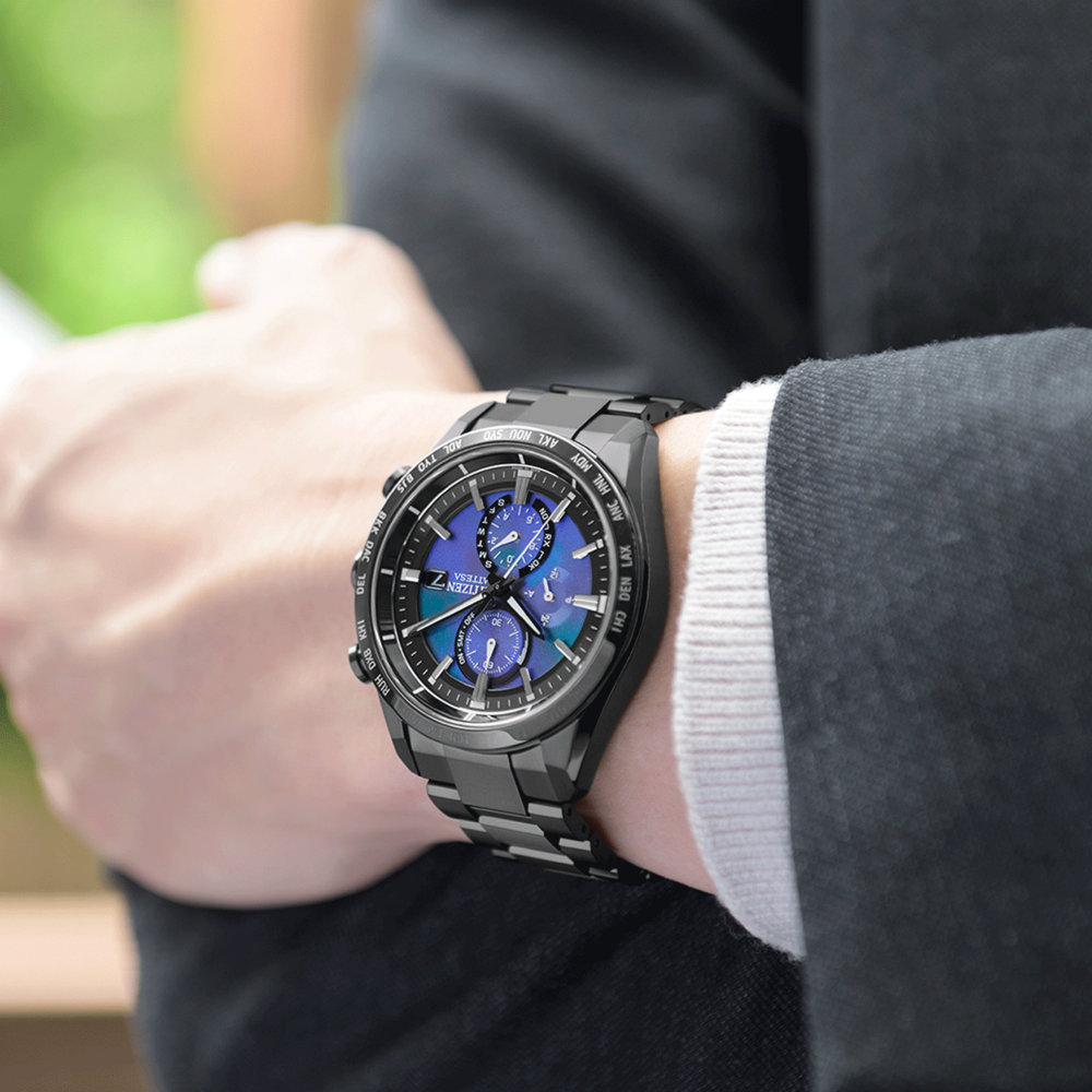 Gros plan d'une montre noire au poignet, avec un cadran bleu et noir.