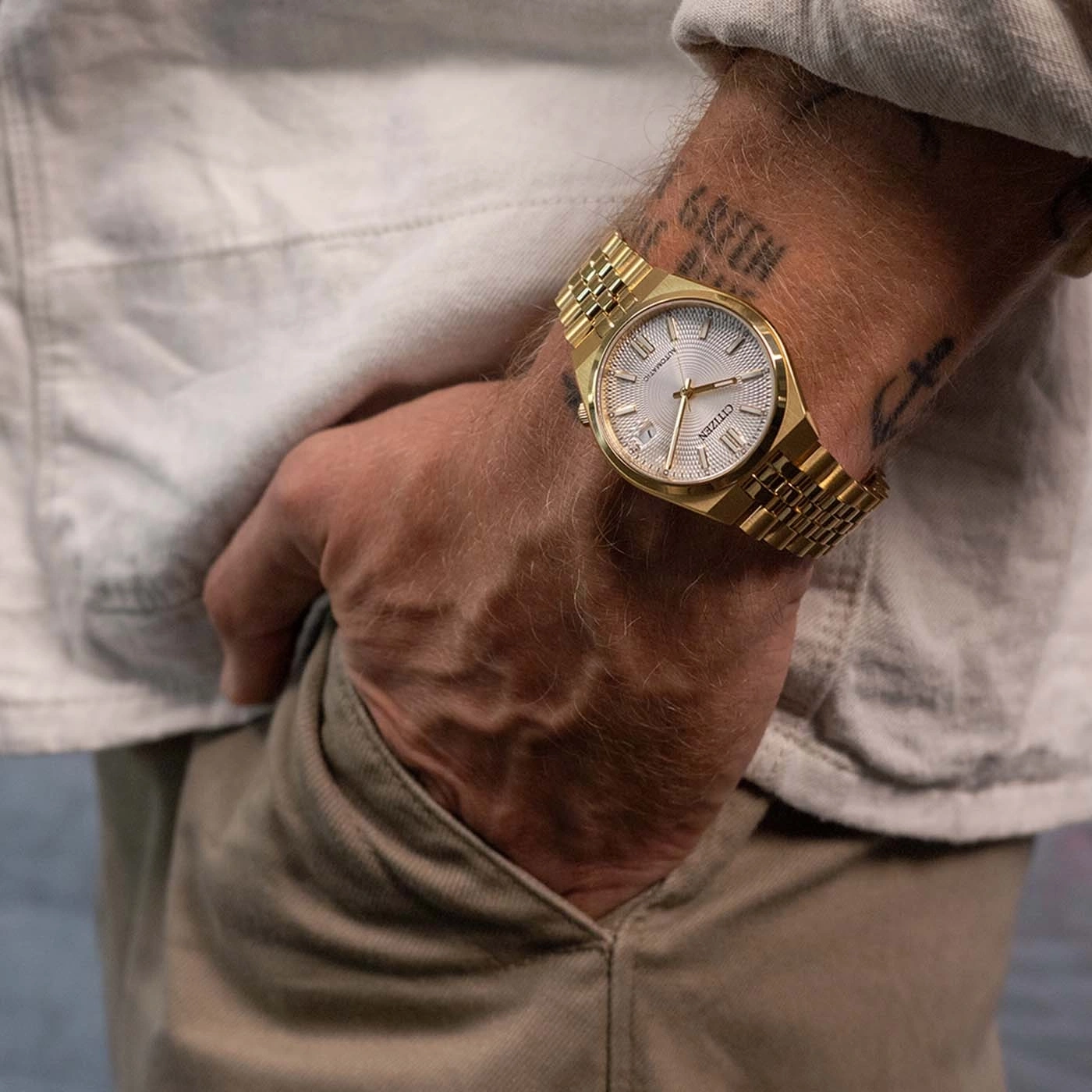 Homme portant une montre Citizen dorée avec un bracelet métallique.