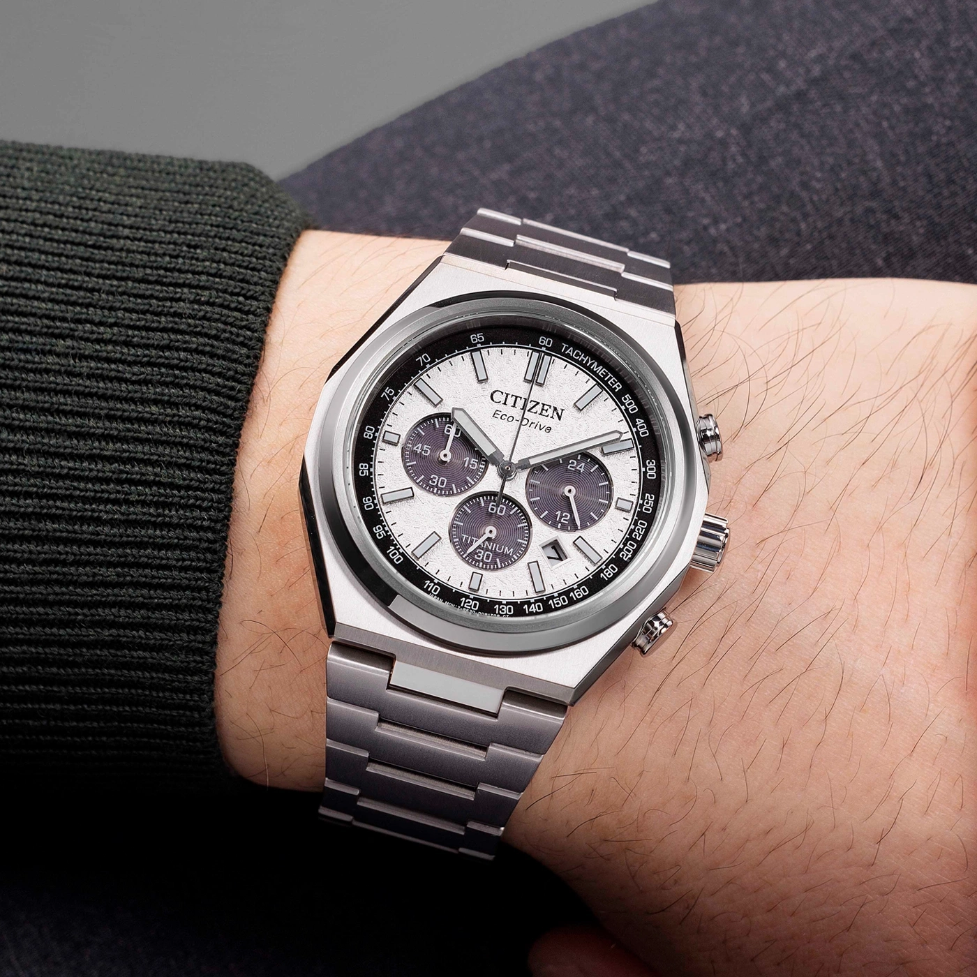 Montre Citizen Eco-Drive en titane sur un poignet masculin avec un pull sombre.