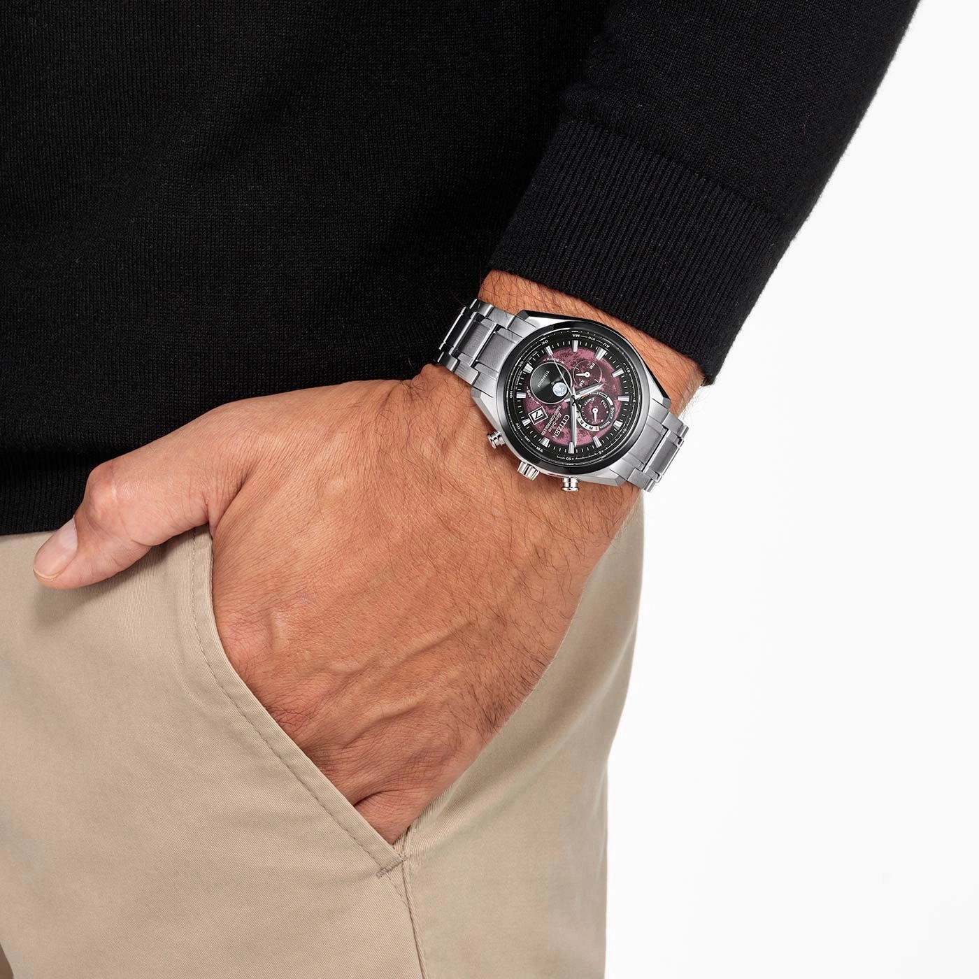 Homme portant une montre Citizen sur un pull noir et un pantalon beige.