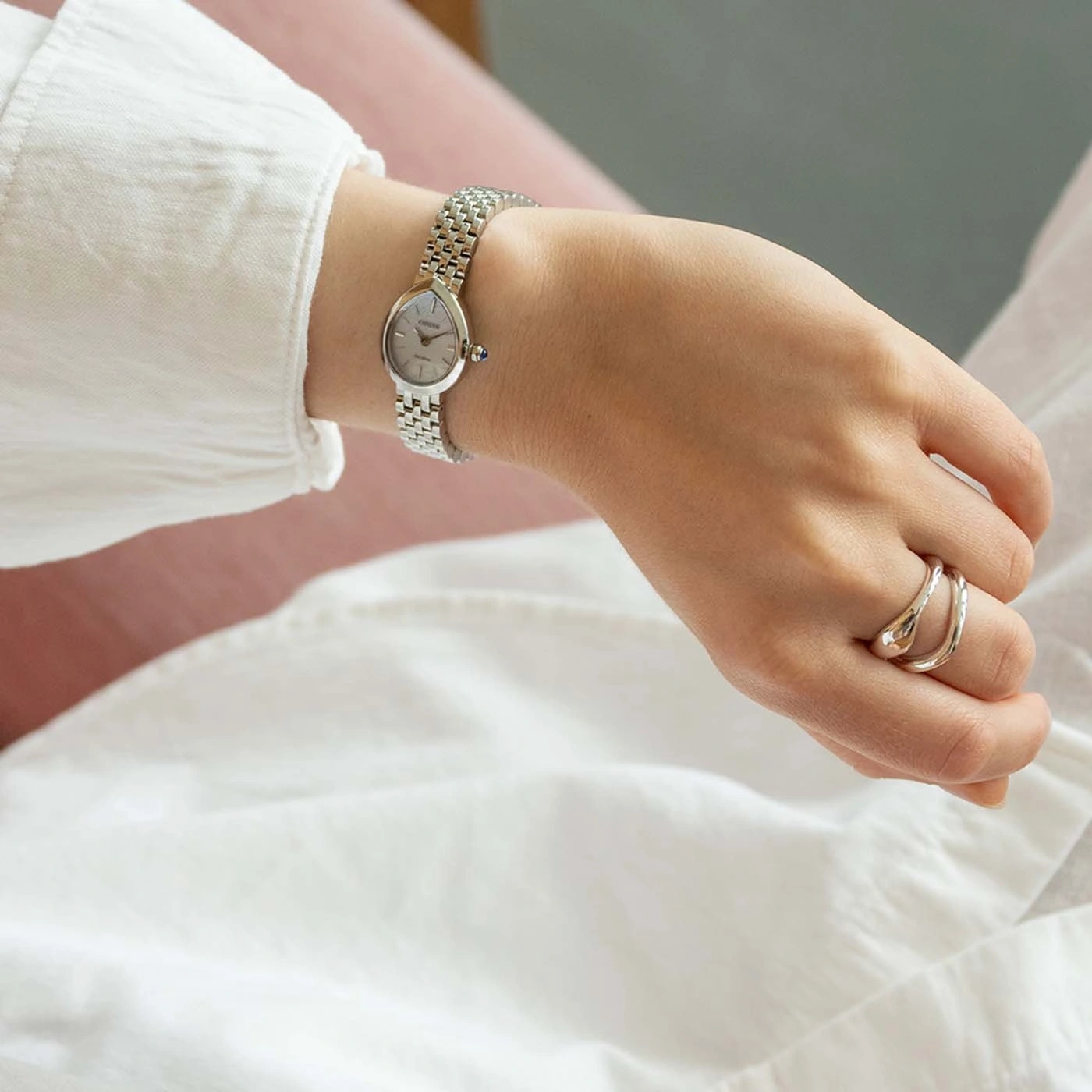 Une femme porte une montre argentée élégante et des bagues fines.
