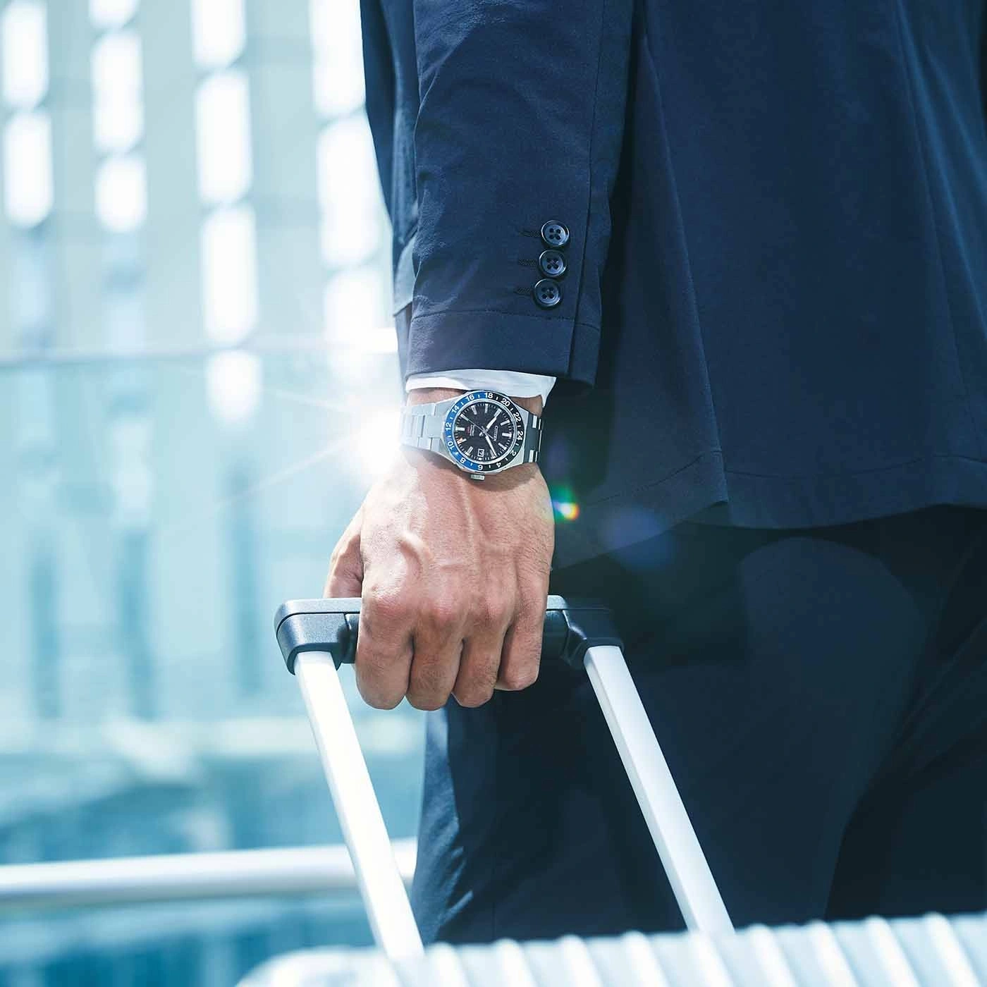Man in suit with watch holding luggage, business travel concept.