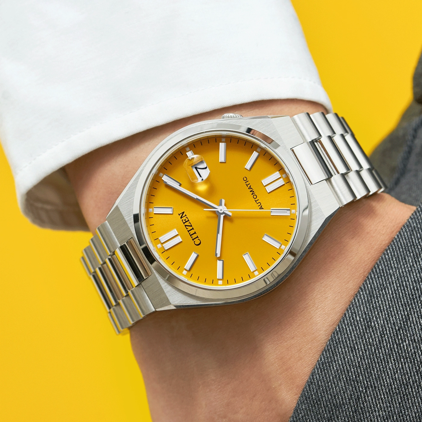 Une montre Citizen automatique avec un cadran jaune vif sur un poignet.