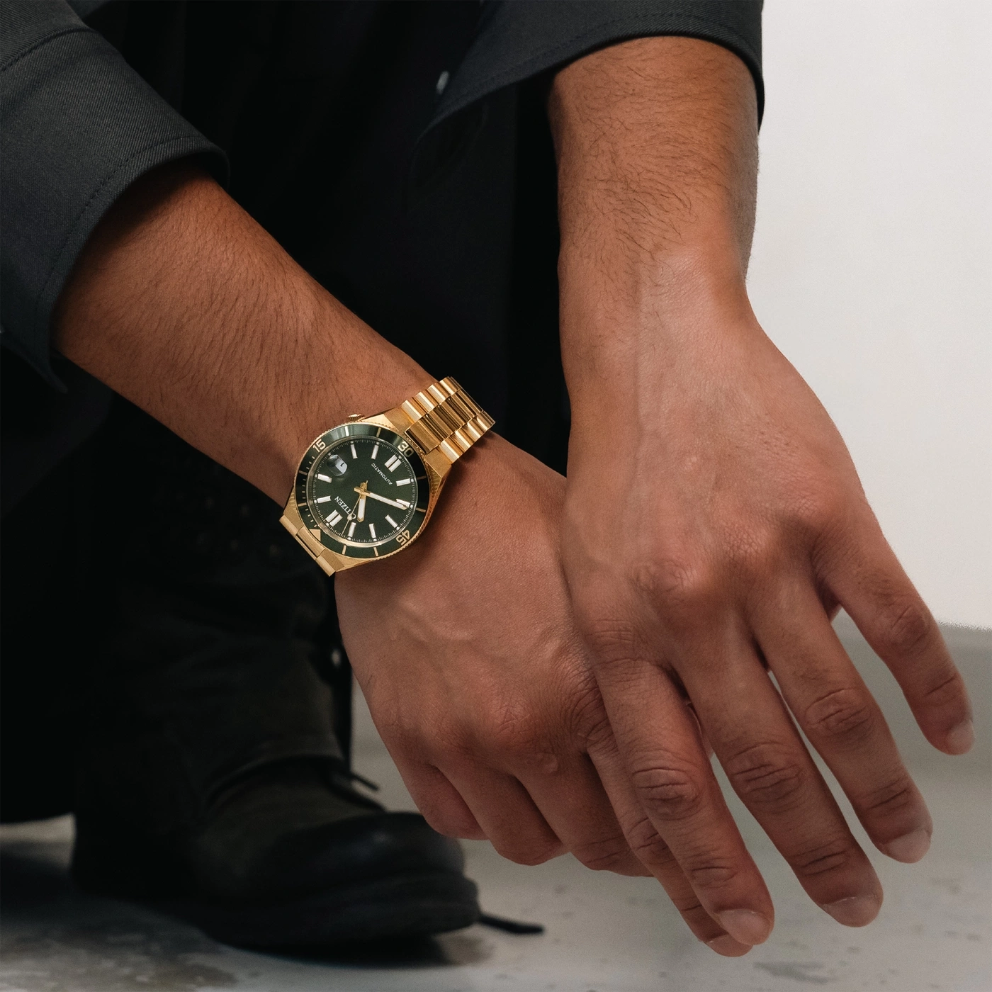 Un homme portant une montre dorée avec un cadran vert sur son poignet.