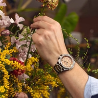 Montre-bracelet d'homme avec des fleurs. Une personne arrange des fleurs avec une montre.