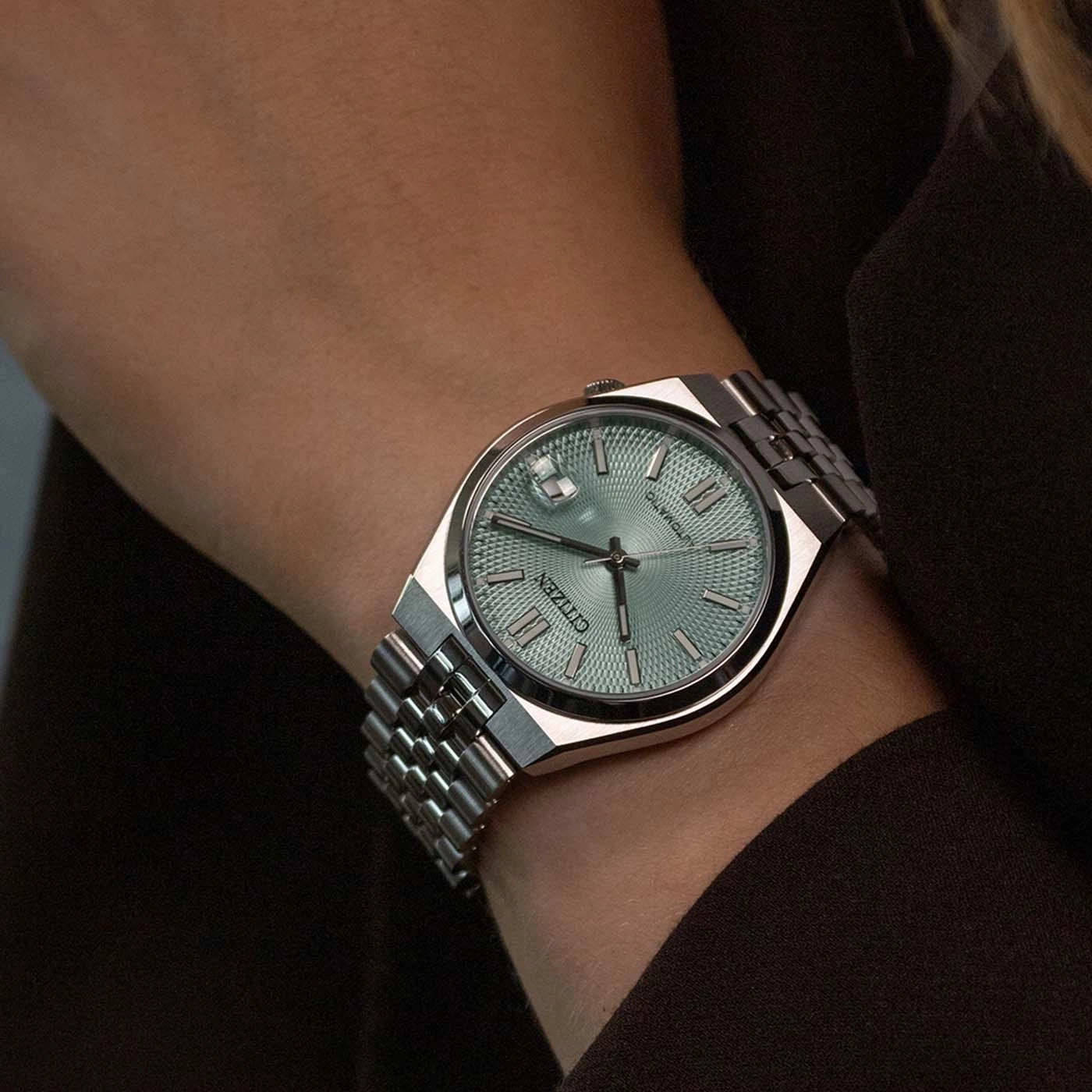 Montre Citizen argentée avec cadran bleu pâle sur un poignet.